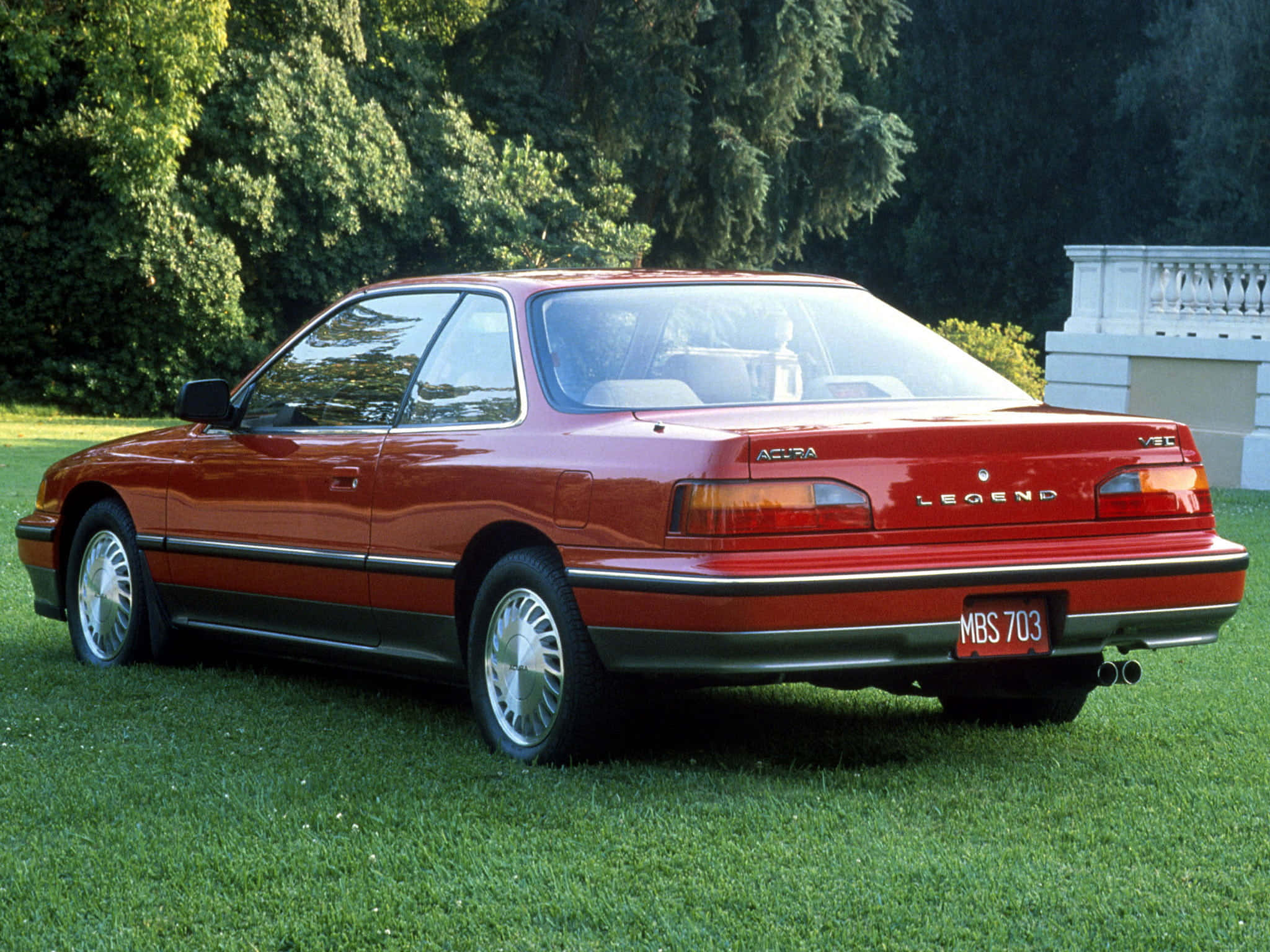 Acura Legend 桌布 壁紙 — 一架亮紅色Acura Legend轎跑車停泊在茂盛綠色草坪上，背景有樹木和白色欄杆。
