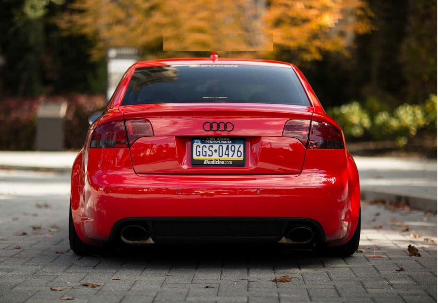 Audi Rs4 桌布 壁紙 — 一輛亮紅色奧迪轎車停在磚砌人行道上，周圍環繞著秋葉。