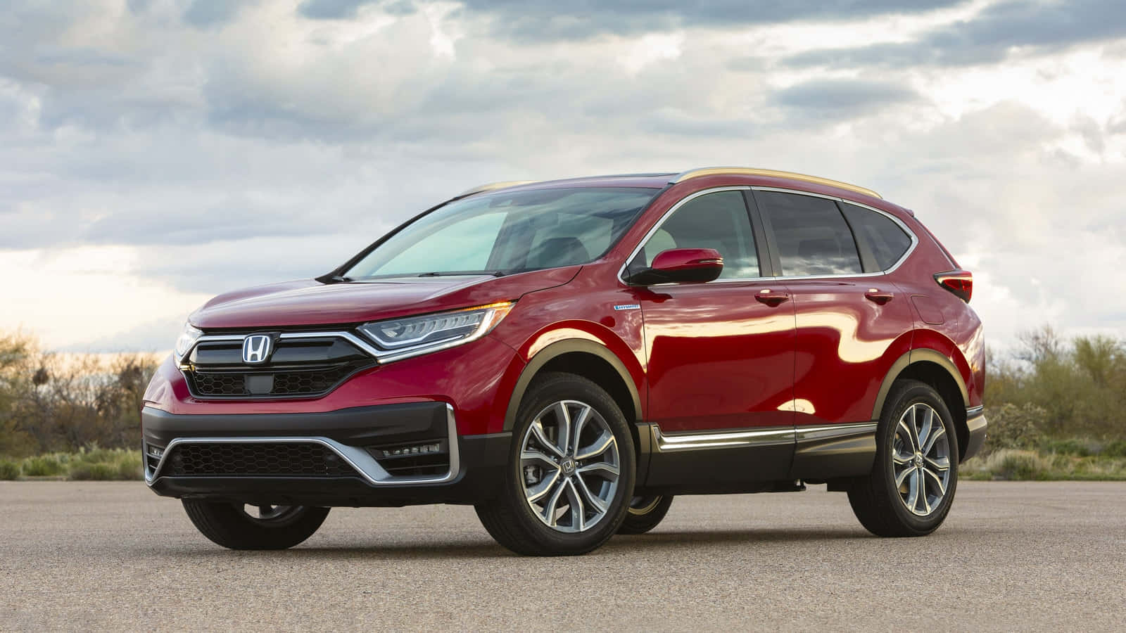 Honda Cr-v 桌布 壁紙 — 一架亮紅色本田CR-V SUV停泊在瀝青路上，背景是陰天和沙漠灌木。