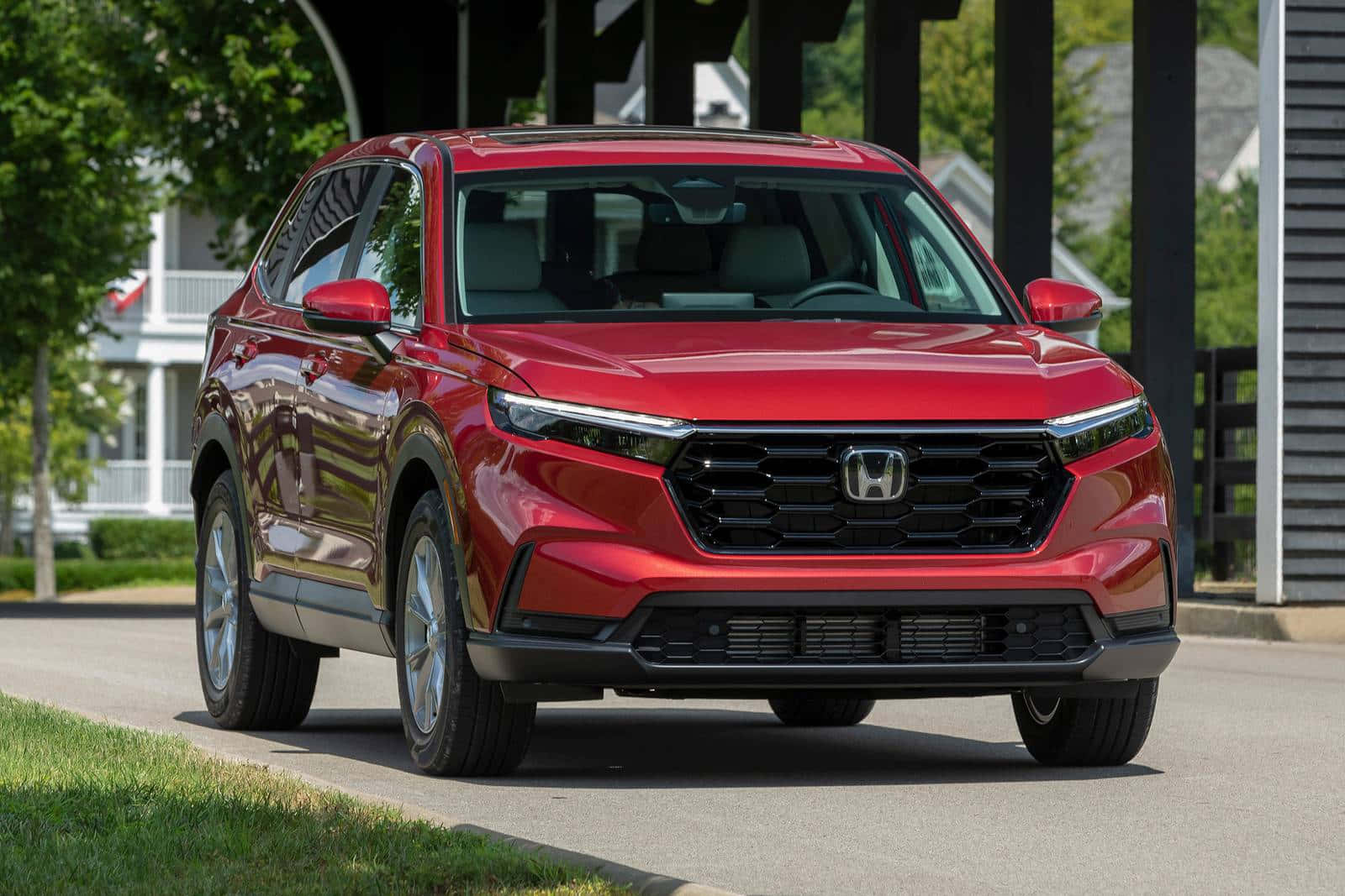 Honda Cr-v 桌布 壁紙 — 一輛亮紅色本田SUV在明亮的日光下停泊在郊區街道上，背景有綠樹和房屋。