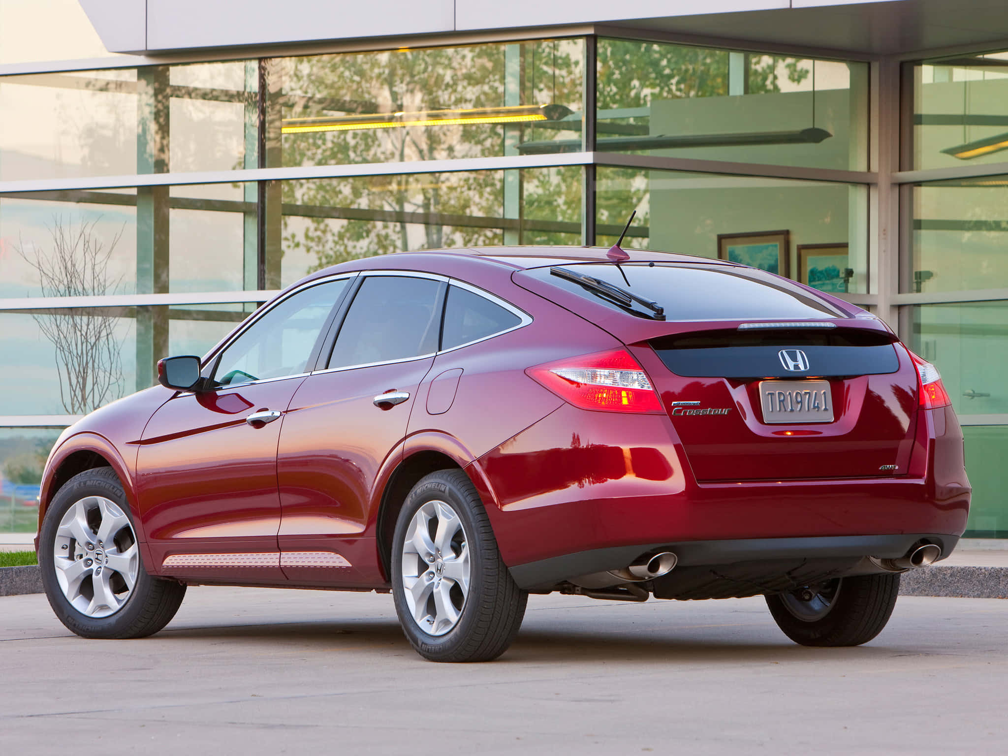 Honda Crosstour 桌布 壁紙 — 一輛亮紅色的本田 Crosstour SUV 停在一棟現代玻璃建築外，玻璃反射出樹木和室內燈光。