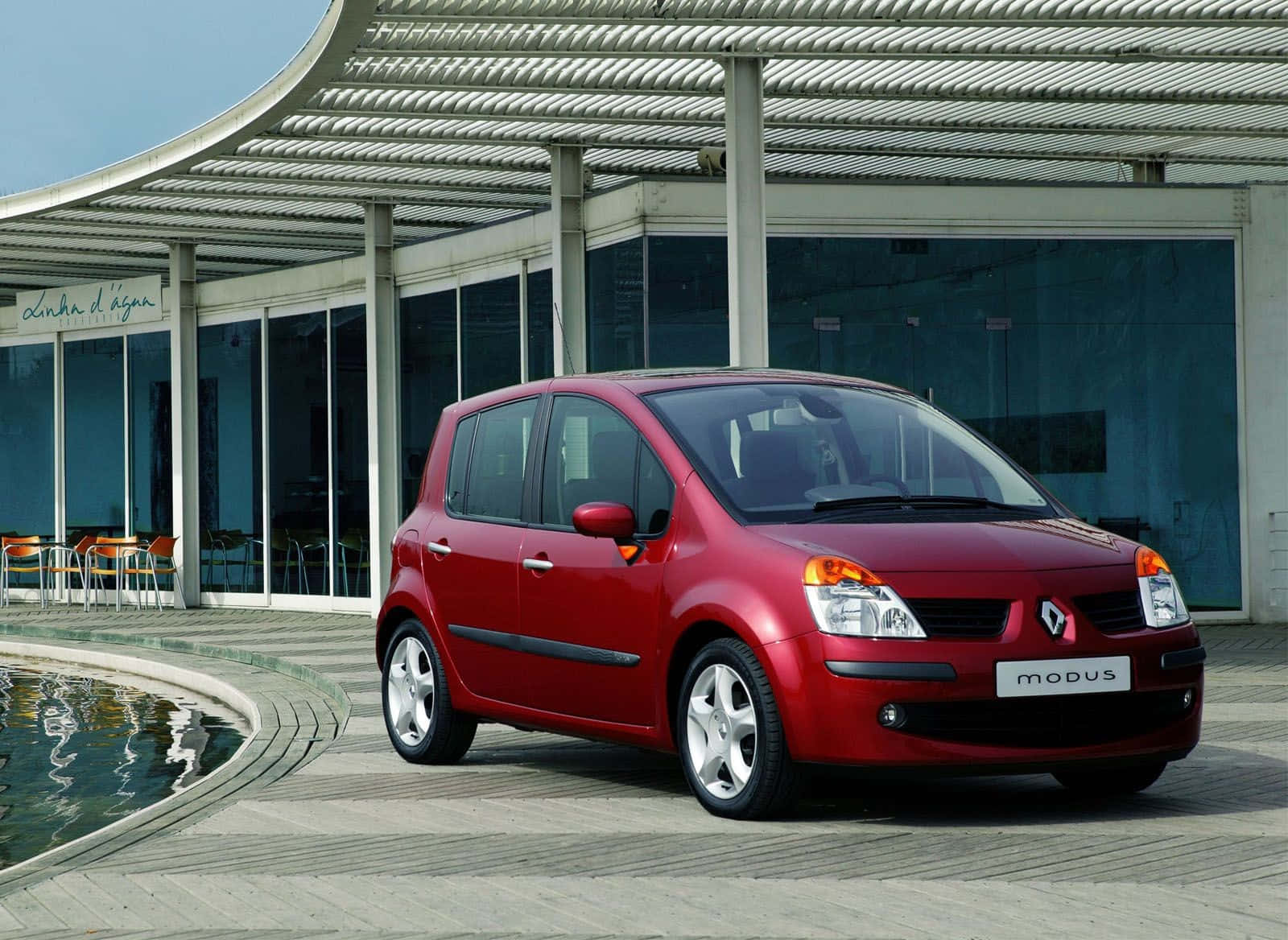 Renault Modus 桌布 壁紙 — 一輛亮紅色的雷諾Modus停放在現代金屬簷篷下，旁邊是彎曲的水景。