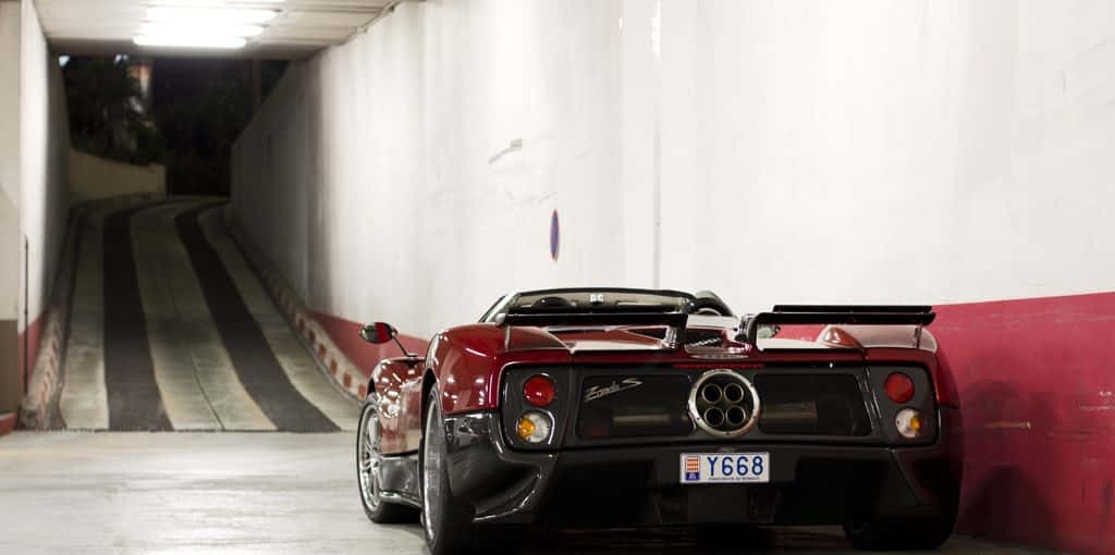 Pagani Zonda C12 Roadster 桌布 壁紙 — 一架亮紅色法拉利F430 Spider停泊在燈光昏暗、帶有條紋坡道的地下停車場。