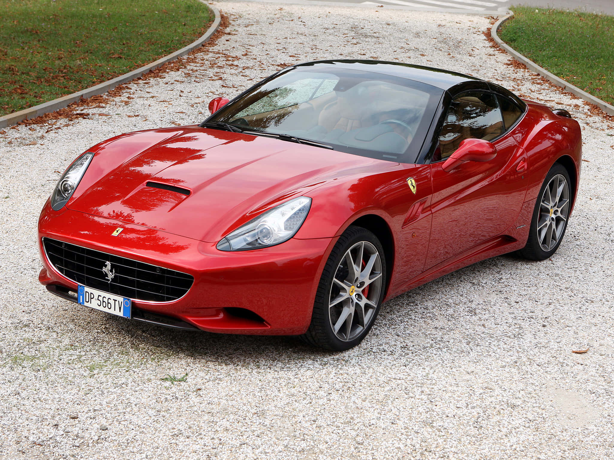 Ferrari Ff 桌布 壁紙 — 一架亮紅色法拉利加利福尼亞跑車停泊在碎石車道上，附近有草和落葉。