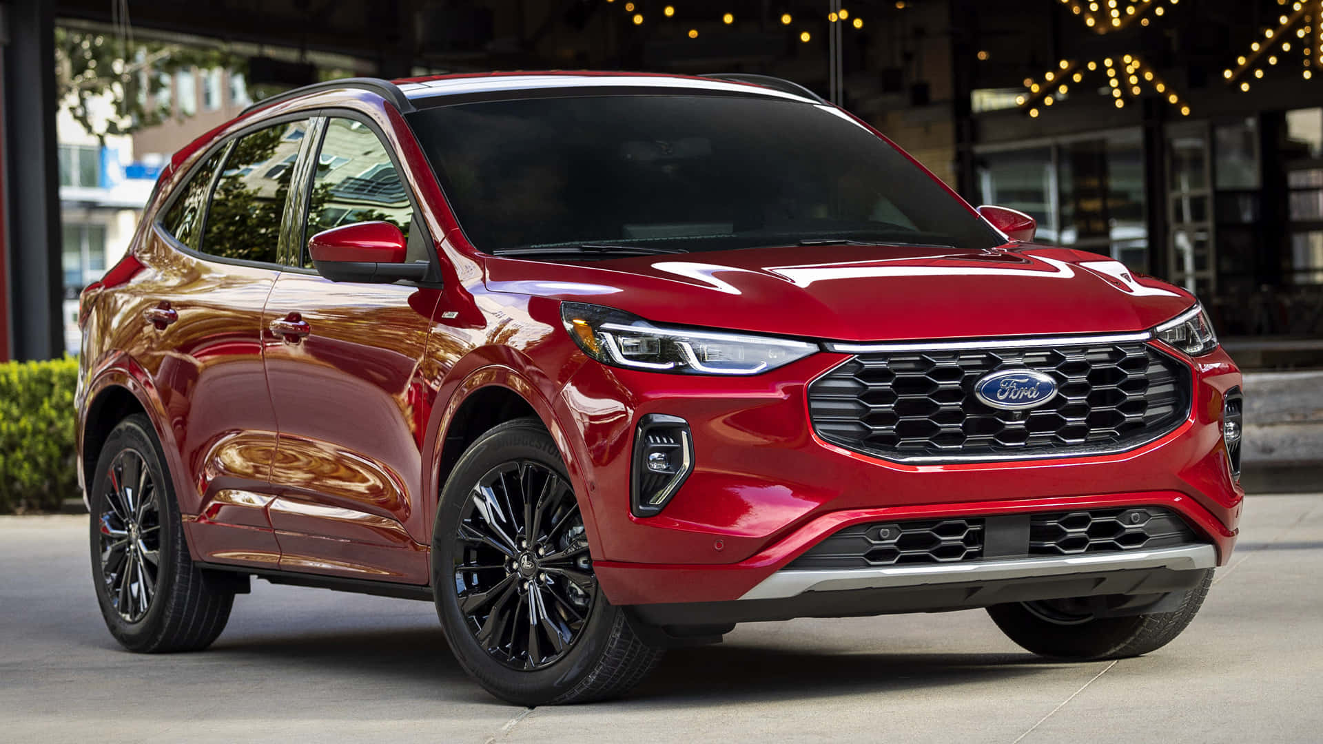 Ford Escape 桌布 壁紙 — 一輛亮紅色福特SUV停在城市行人路上，上方有燈串，背景為現代建築。