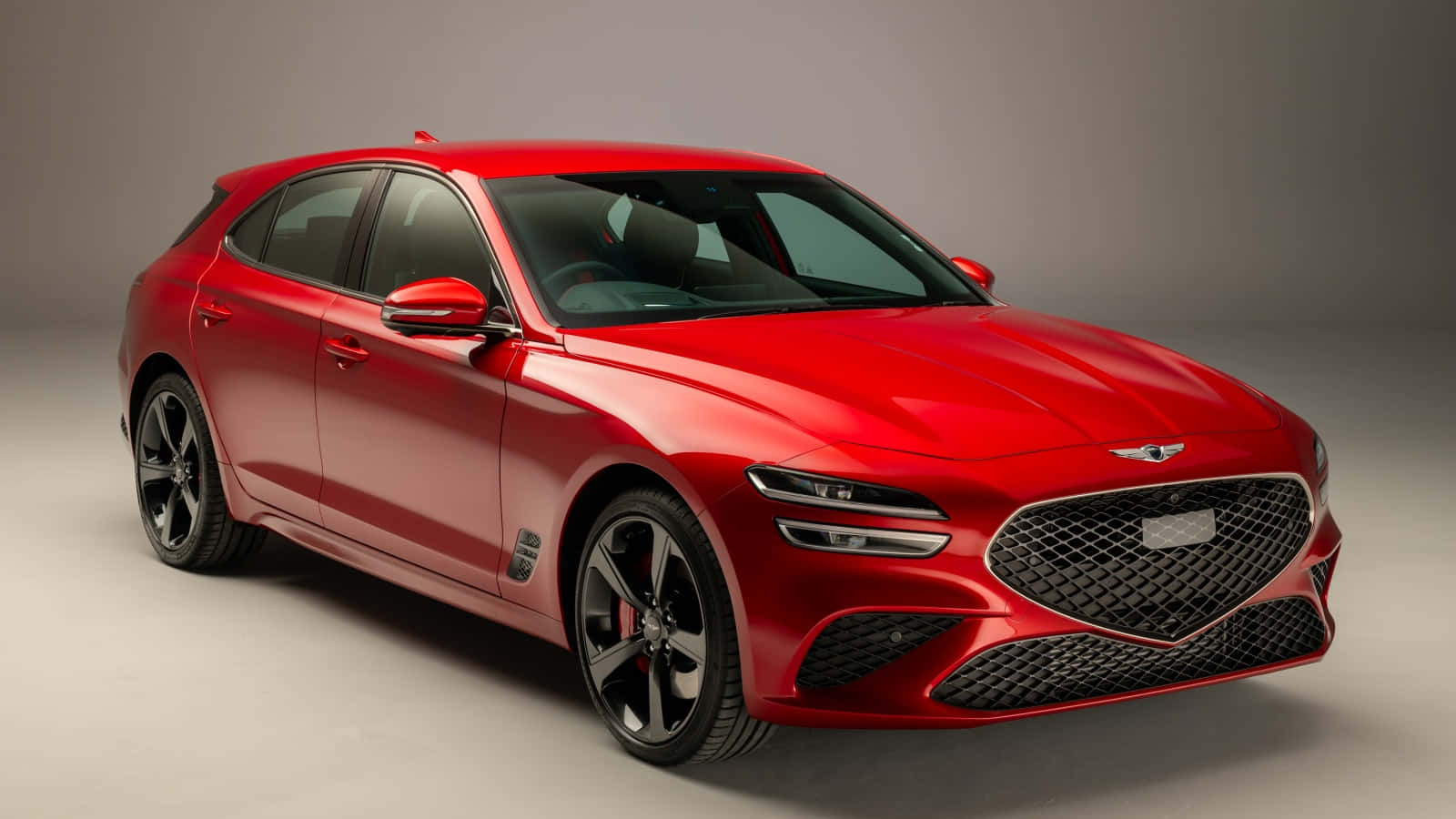 Genesis G70 桌布 壁紙 — 一輛亮紅色Genesis G70運動轎車，配備黑色輪圈和激進的前格柵，在灰色工作室背景前擺拍。