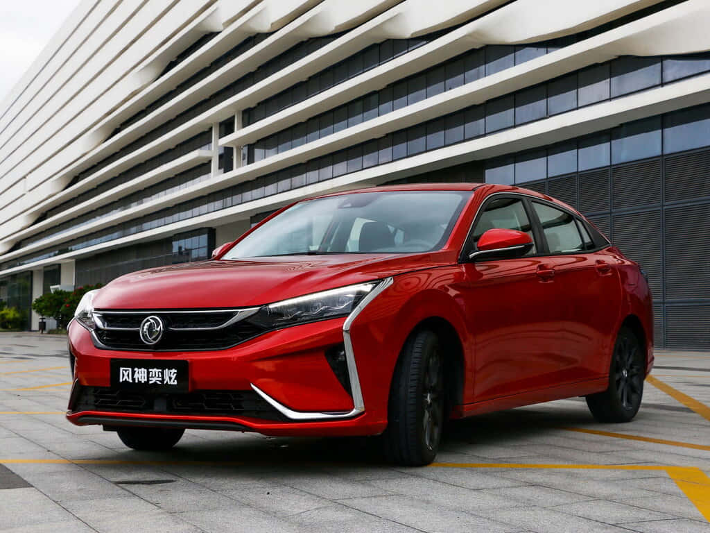  壁紙 — 一輛亮紅色轎車停在一棟現代玻璃和混凝土建築前，天氣晴朗。