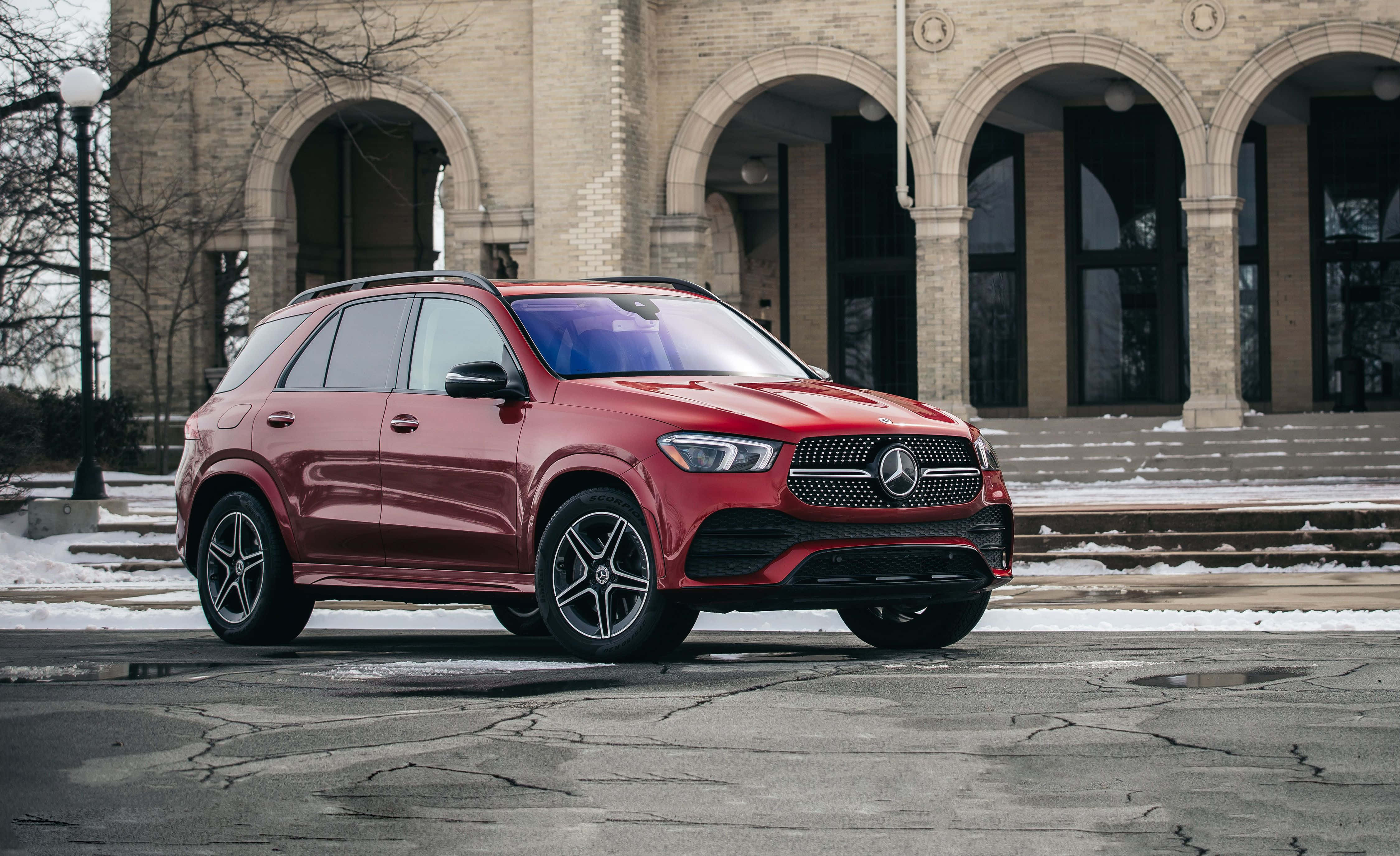 Mercedes Benz Gle-class 桌布 壁紙 — 一架亮紅色Mercedes-Benz SUV停泊在雪地行人路上，前方是一座有拱形入口的宏偉石建築。