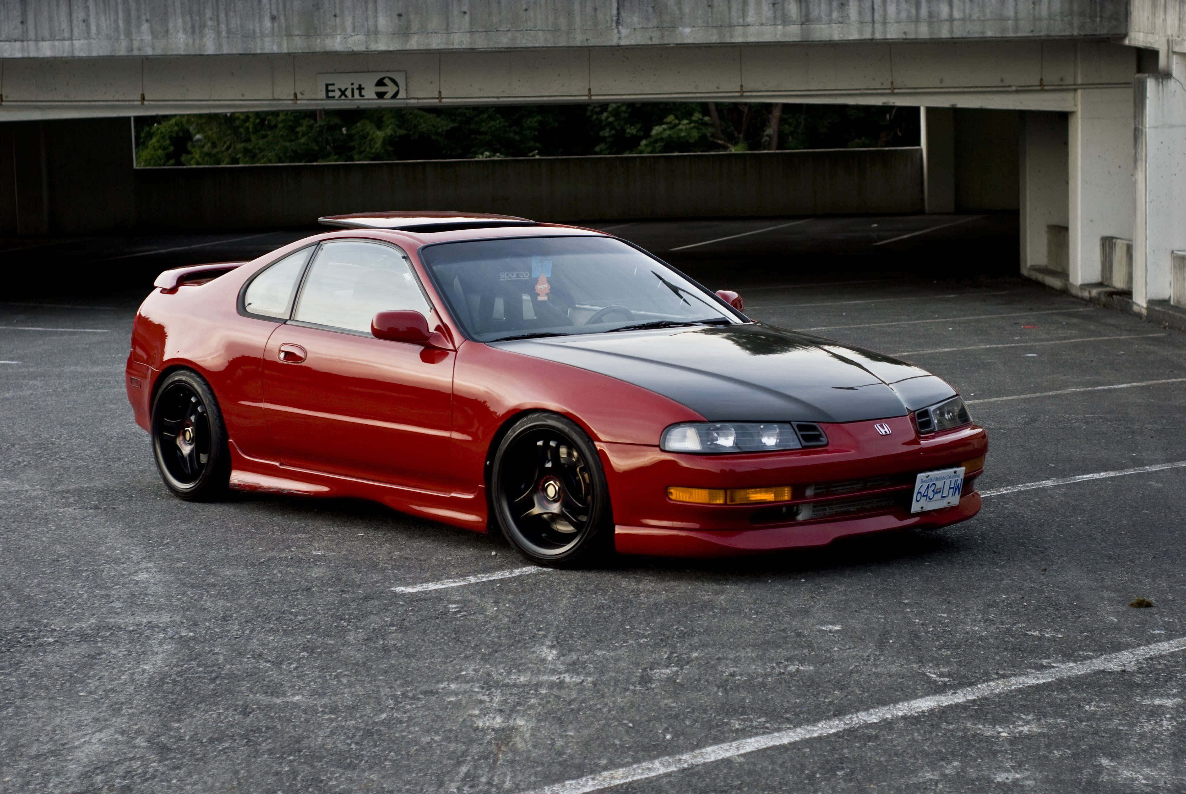 Honda Prelude 桌布 壁紙 — 一輛亮面紅黑色跑車停泊在混凝土高架橋下，背景可見綠植。