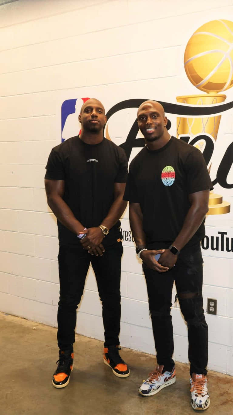 兩名身穿黑色服裝的男子在NBA總決賽牆壁藝術前擺姿勢。