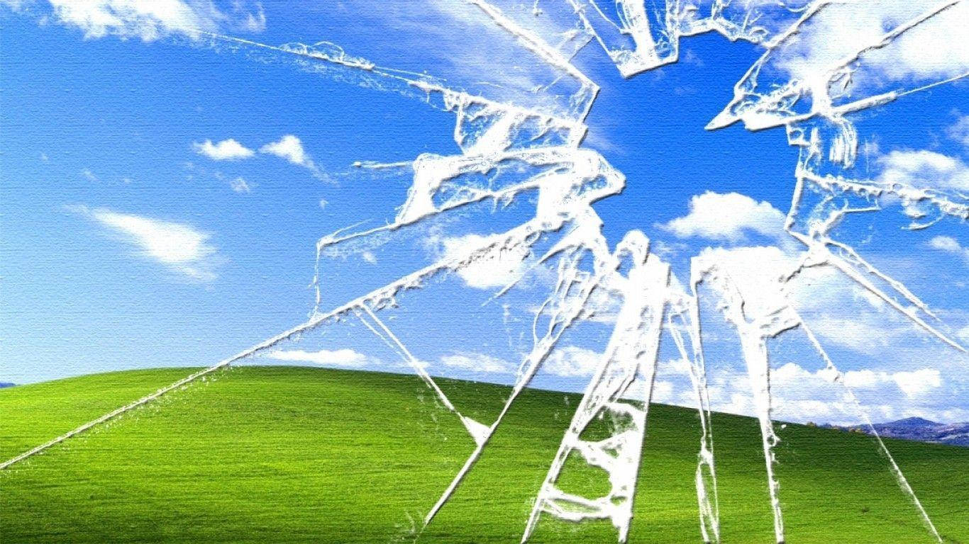 裂紋玻璃效果覆蓋在經典的綠色山丘和藍天Windows XP桌布上。