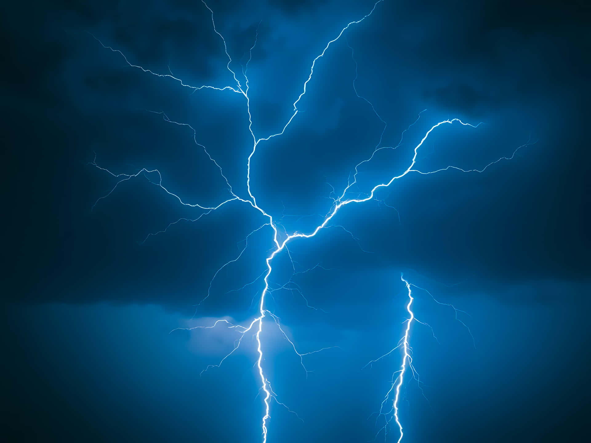 一道強烈的閃電照亮了深藍色的暴風雨天空。