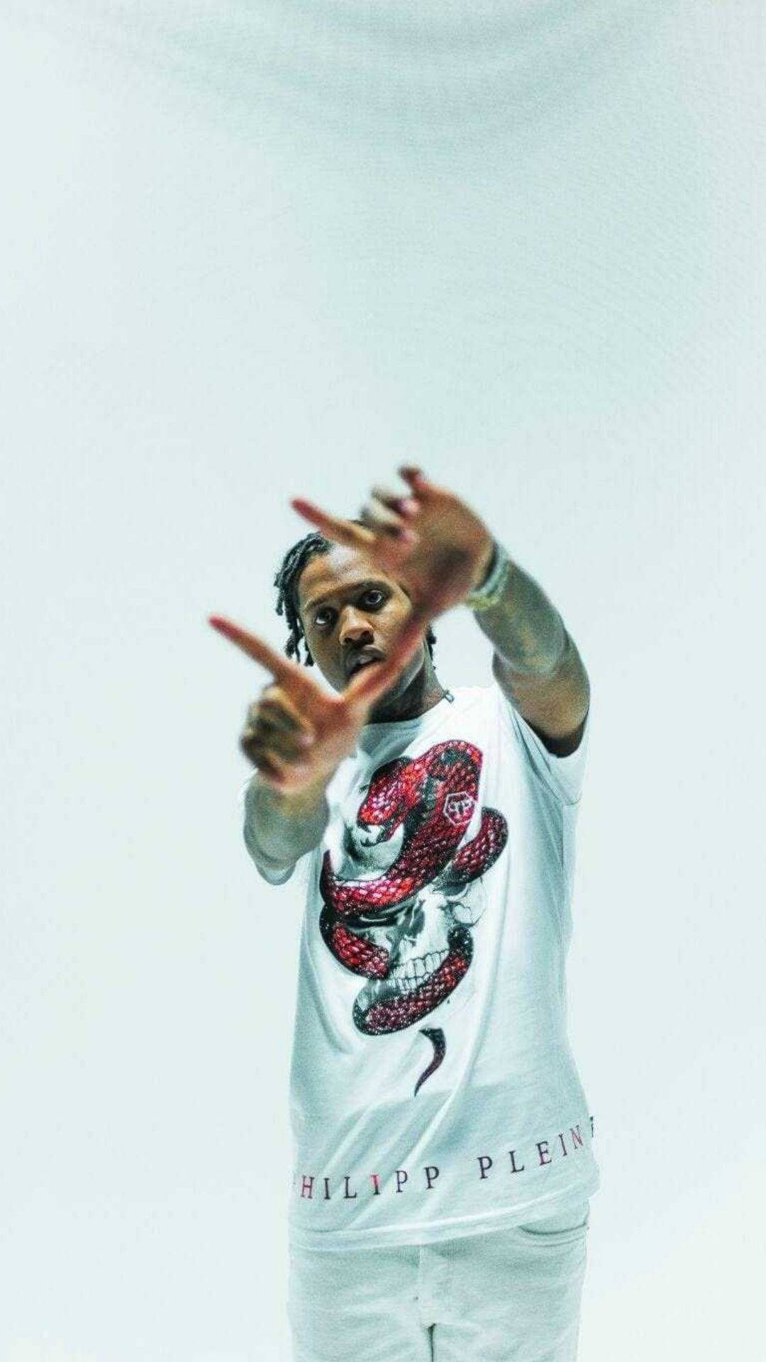 Lil Durk 在純白房間內 壁紙 — 一名身穿白色 Philipp Plein T 恤（帶有紅色蛇形圖案）的男子，在純白色背景前直接指向觀看者。