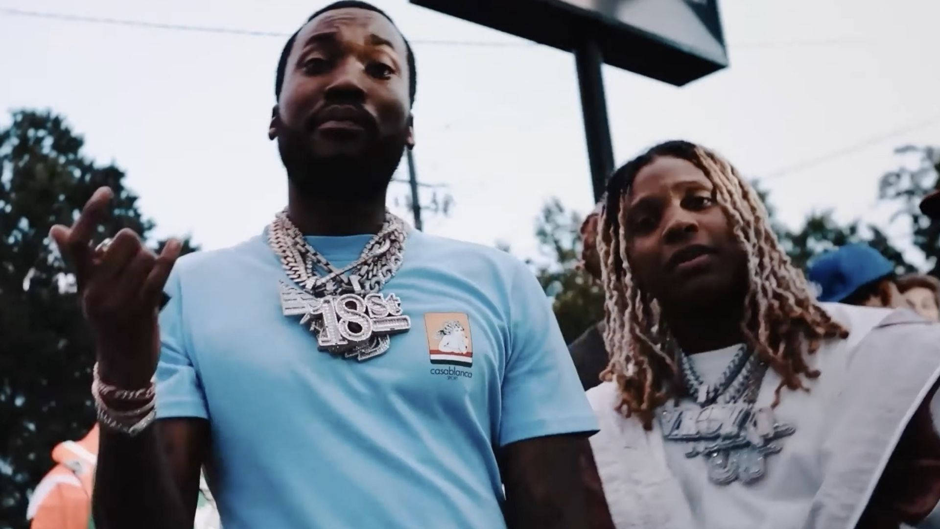 Lil Durk 與 Meek Mill 壁紙 — 兩名戴著鎖鏈和辮子髮型的男子在陰天戶外自信地擺姿勢。