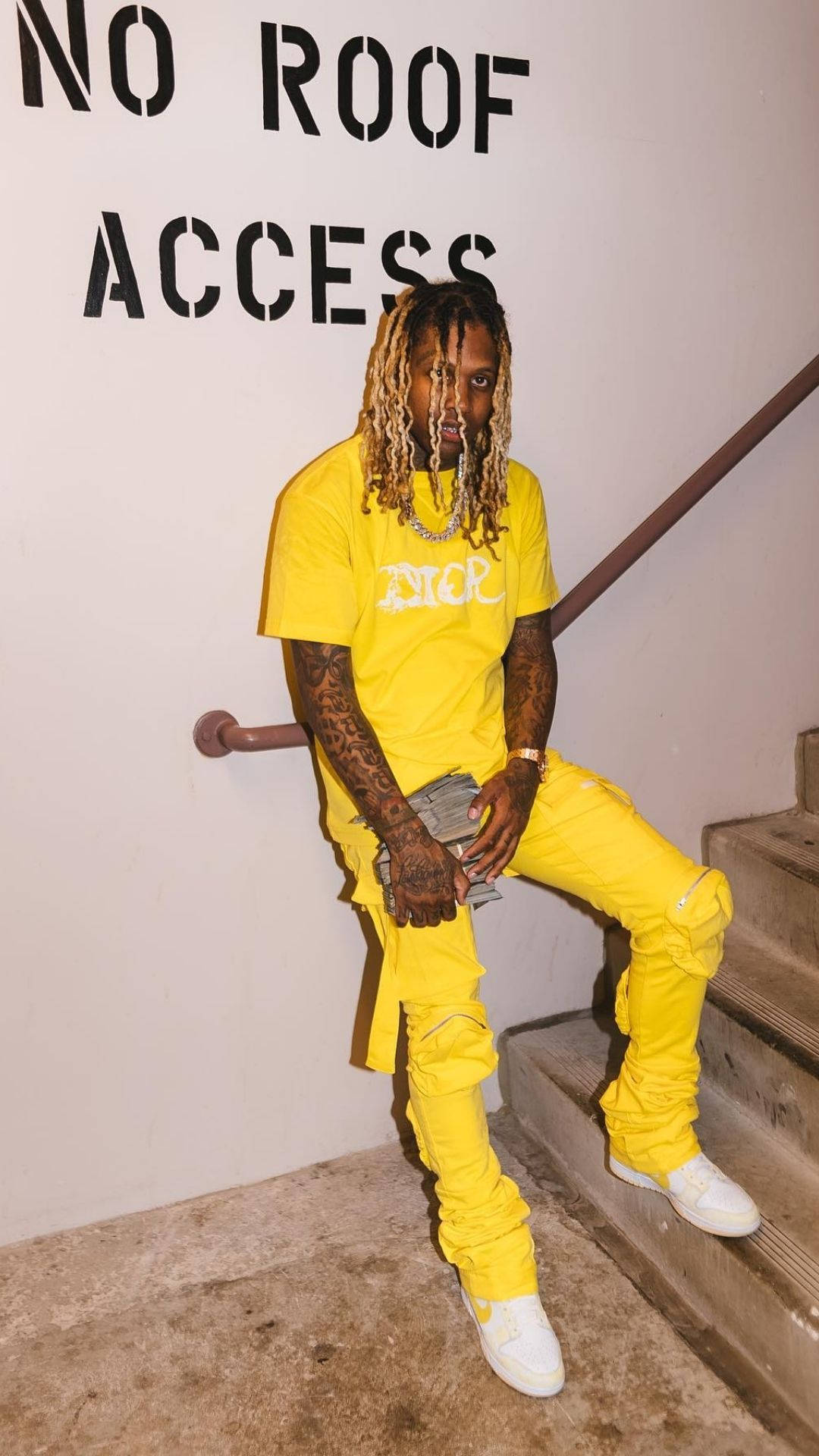 Lil Durk 靠牆階梯 壁紙 — 一名身穿亮黃色Dior服裝的男子隨意地坐在混凝土樓梯上，上方有'NO ROOF ACCESS'牆牌。