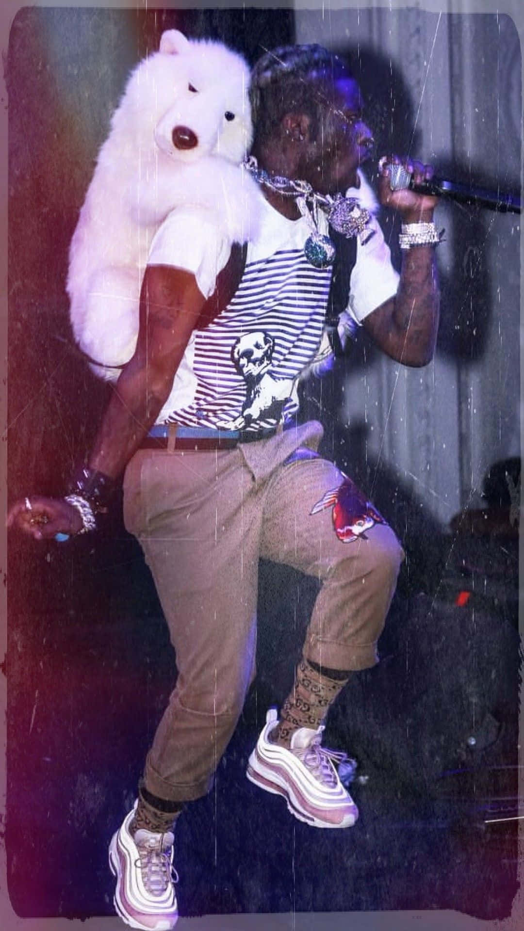 饒舌歌手手持麥克風，肩上放著北極熊毛絨玩具，在現場表演中。