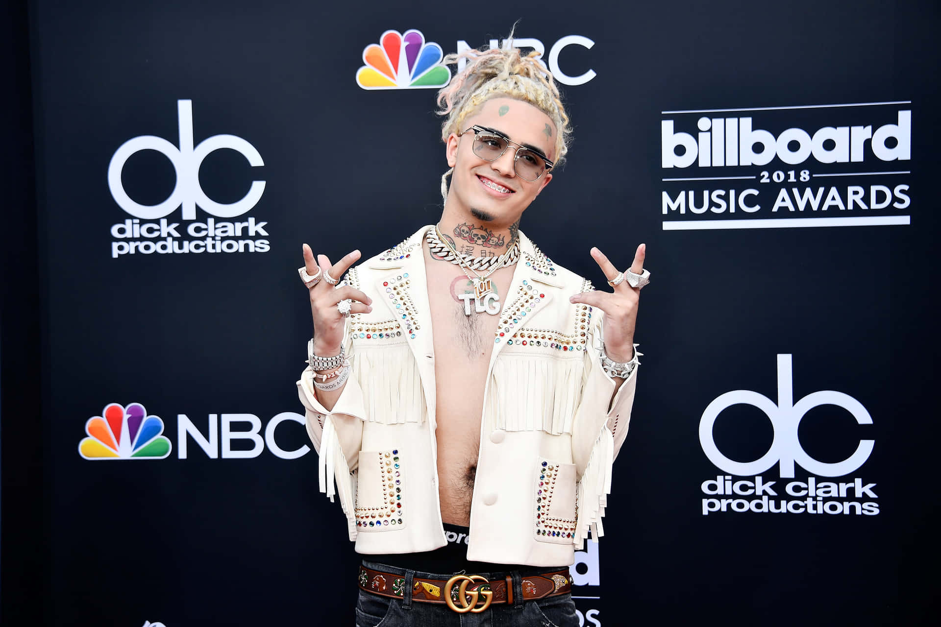 身穿鑲有寶石白色外套的男子在Billboard音樂獎上擺姿勢。