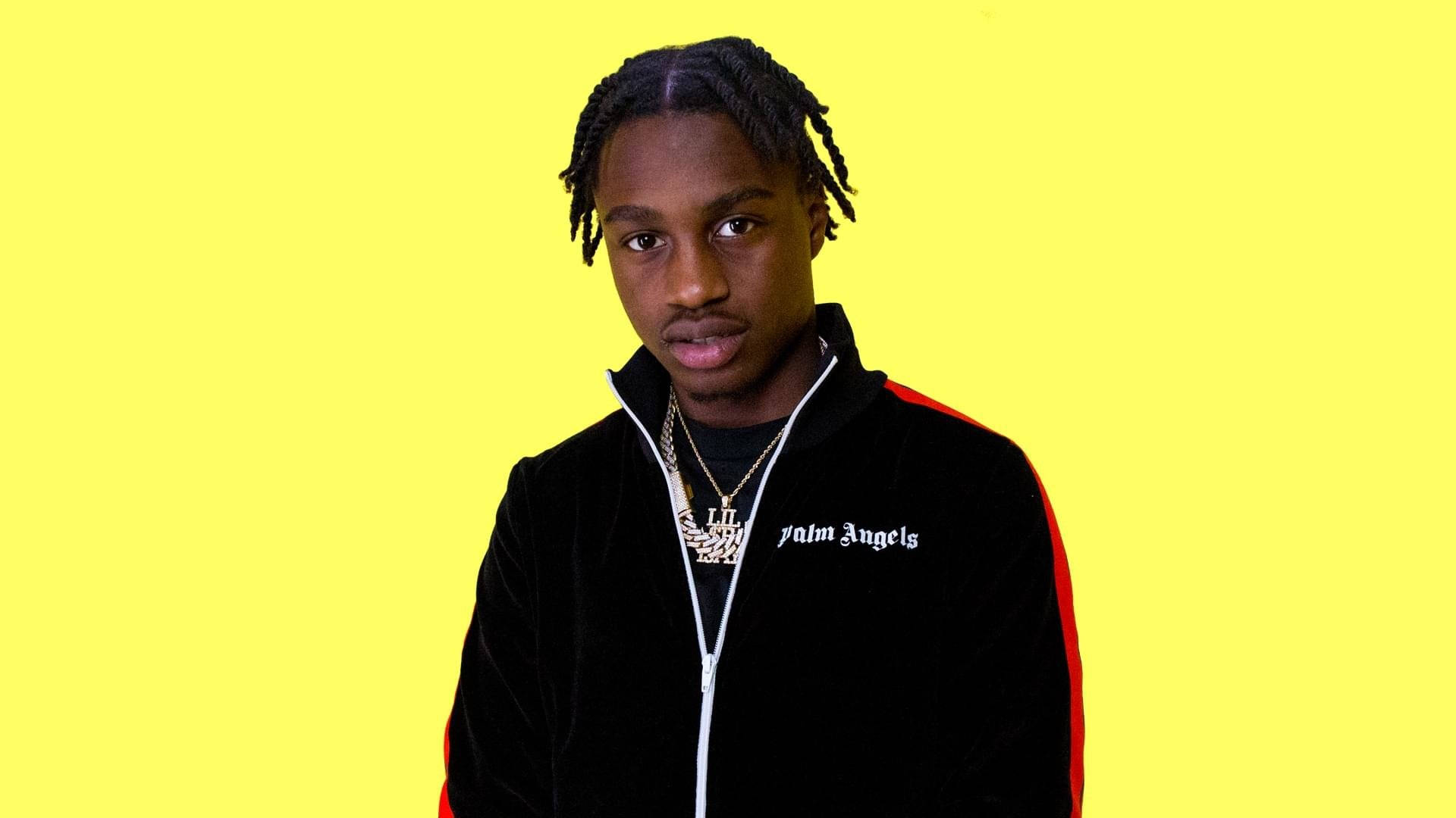Lil Tjay 狂野姿態 壁紙 — 一位辮子頭髮的年輕男子穿著黑色天鵝絨Palm Angels外套，背景為明亮的黃色。
