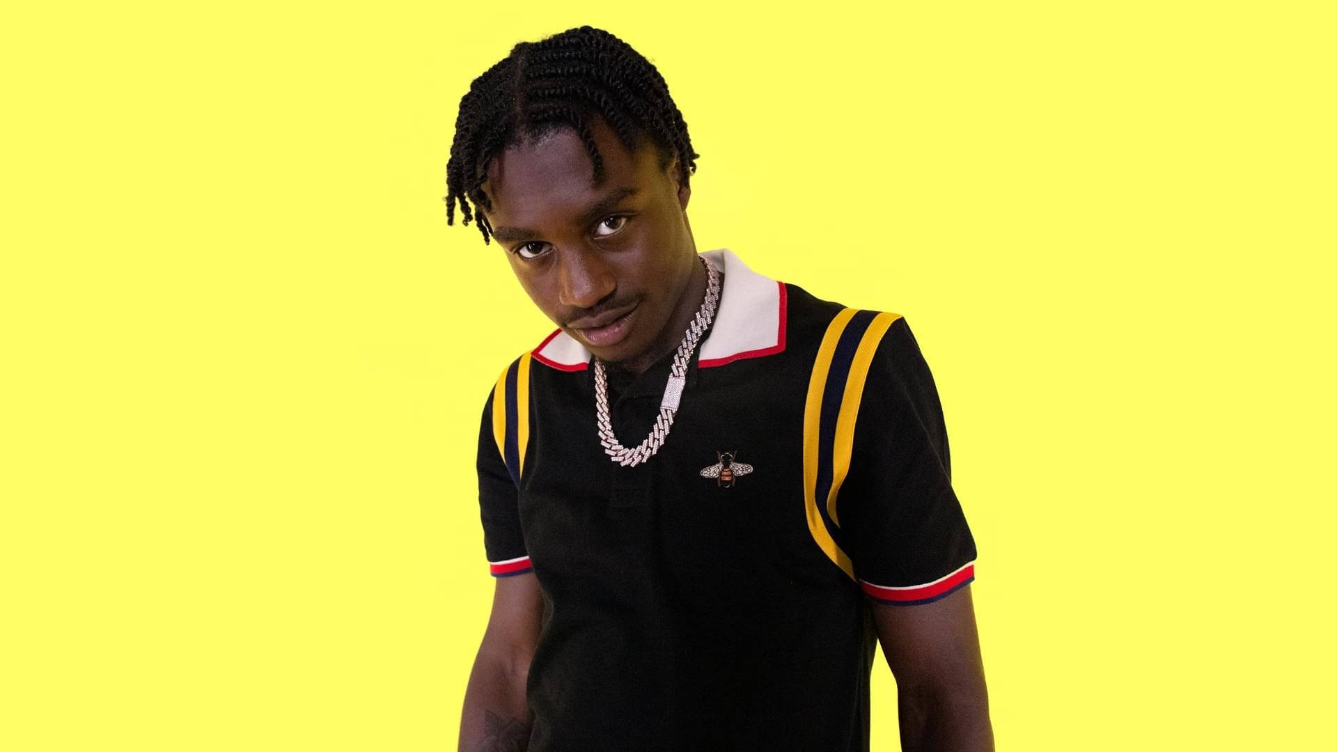 Lil Tjay 的歌曲 TN 壁紙 — 一位辮髮年輕男子穿著帶有黃色條紋的黑色Polo衫和銀色項鍊，背景為亮黃色。