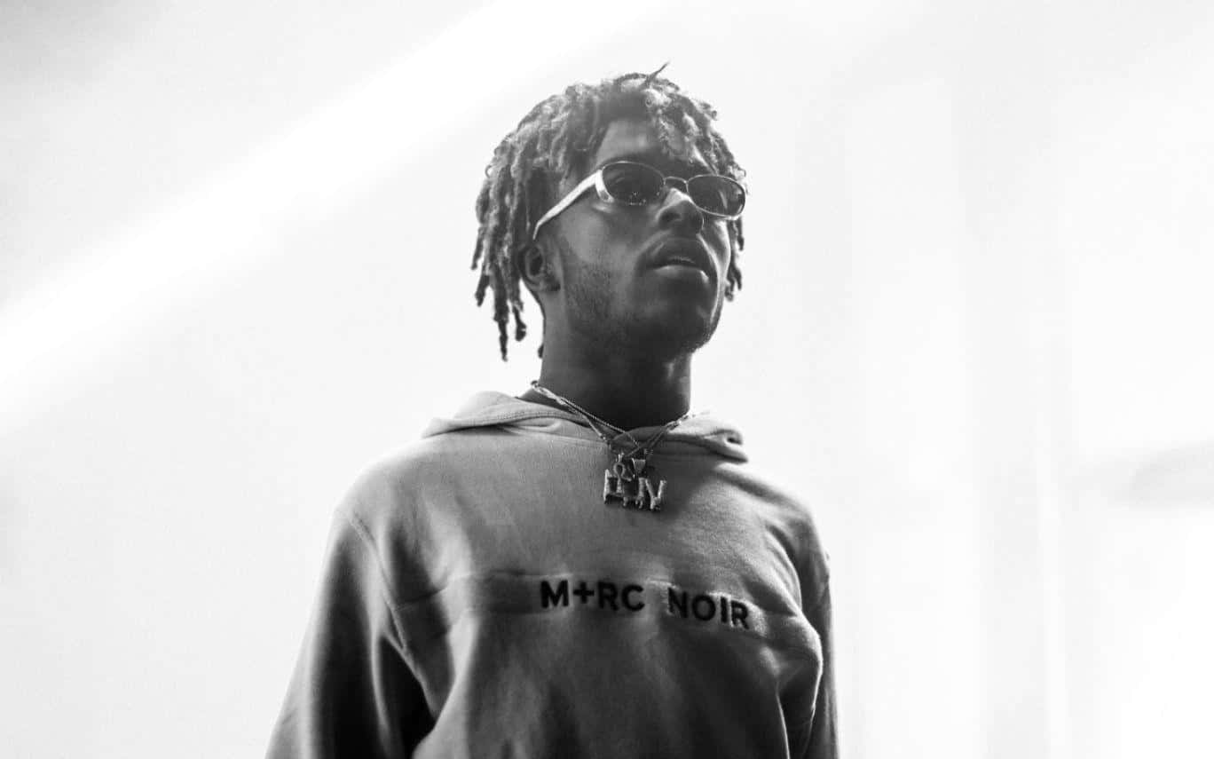 Lil Uzi 手持新專輯《Eternal Atake》 壁紙 — 一個黑白肖像，一名留著辮子頭、戴著太陽眼鏡的男子在明亮背景下向上仰望。