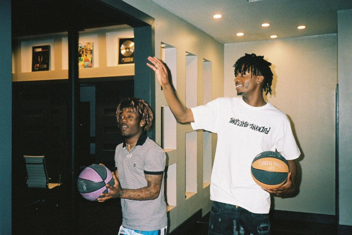 Lil Uzi 與 Playboi Carti PFP 壁紙 — 兩個男人在現代走廊裡拿著籃球，一個向上做手勢，另一個看著一個紫色的球。