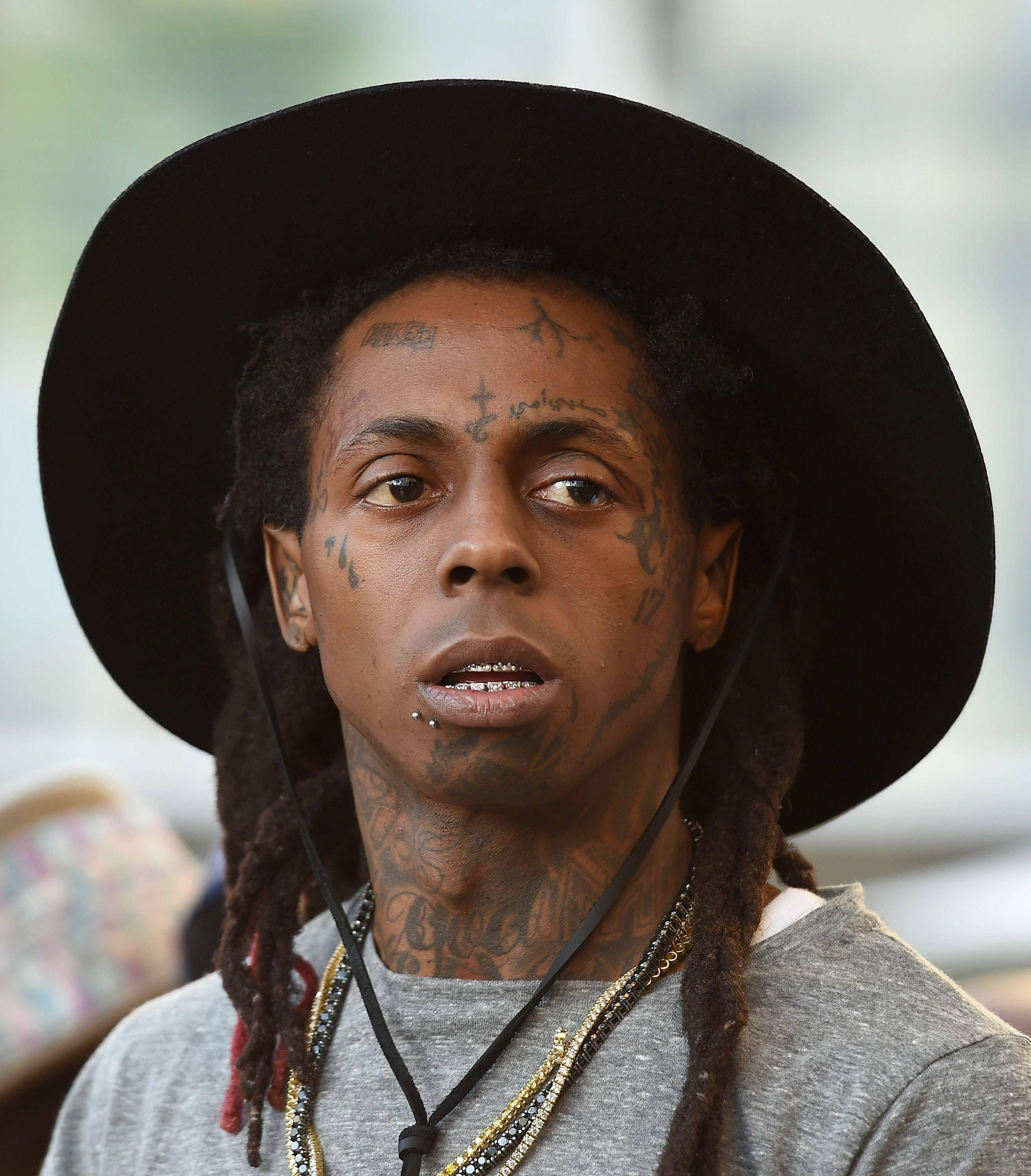 Lil Wayne 上半身特寫 壁紙 — 一名臉上和頸部有紋身的男子，戴著黑色寬邊帽和層疊項鍊的特寫肖像。
