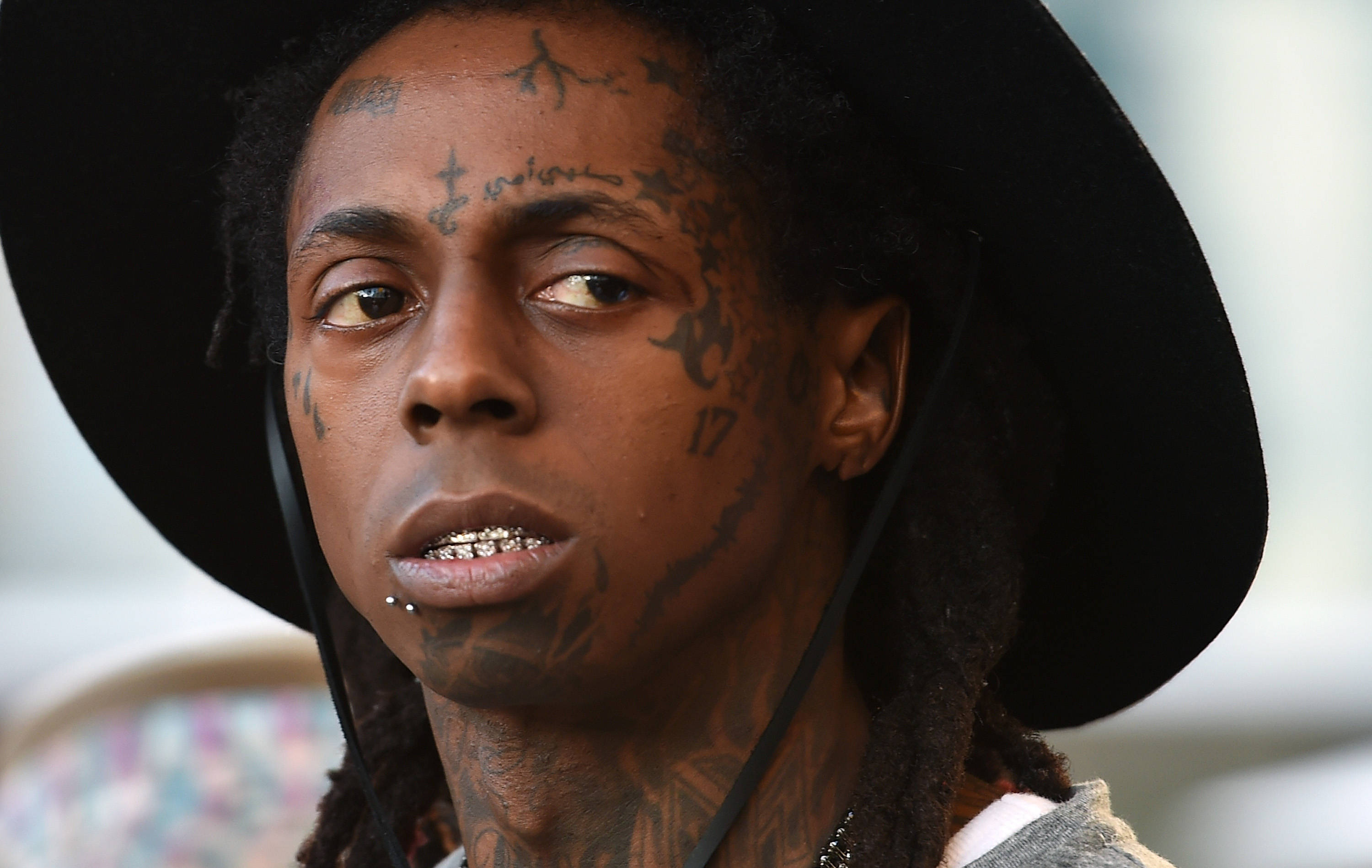 Lil Wayne 直視前方 壁紙 — 一名臉上和頸部有紋身的男子戴著黑色寬邊帽的特寫肖像。