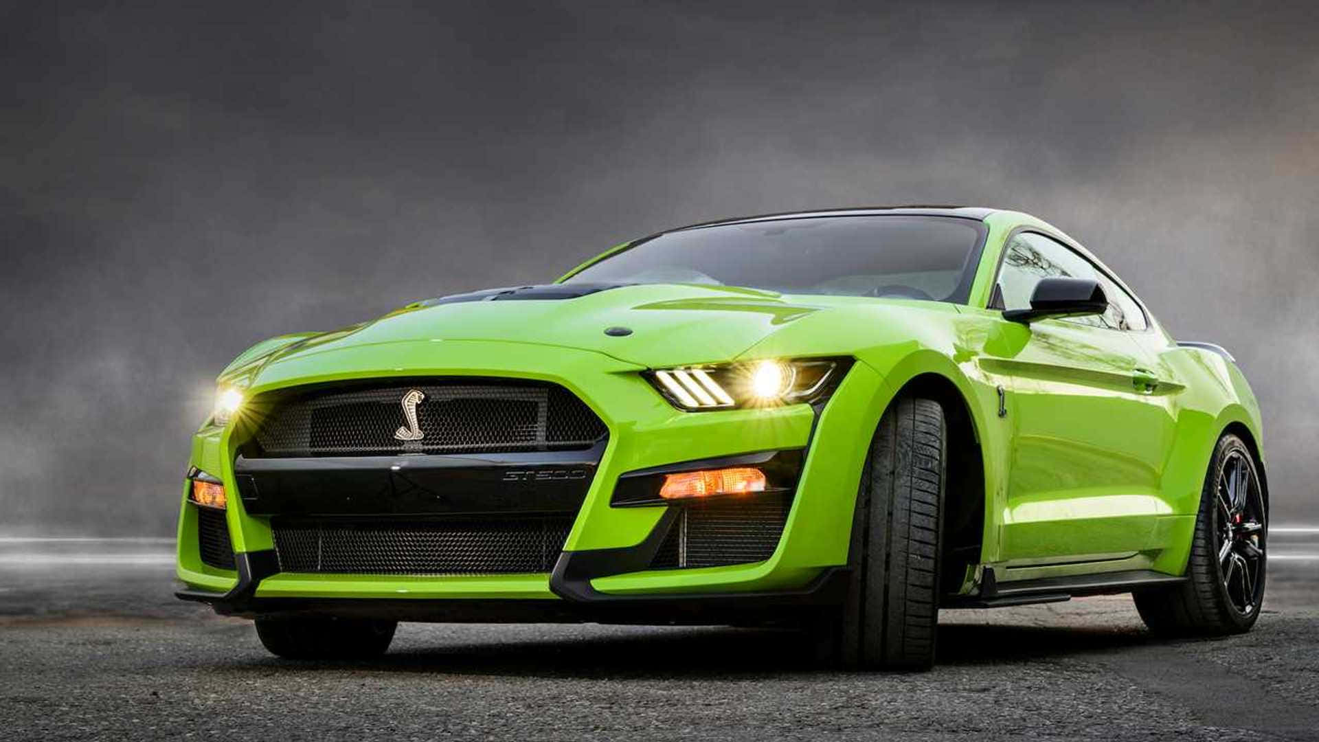 壁紙 — 一輛充滿活力的青檸綠色福特野馬 Shelby GT500，在戲劇性燈光下，以發光的頭燈主導著霧氣瀰漫的灰色瀝青道路。