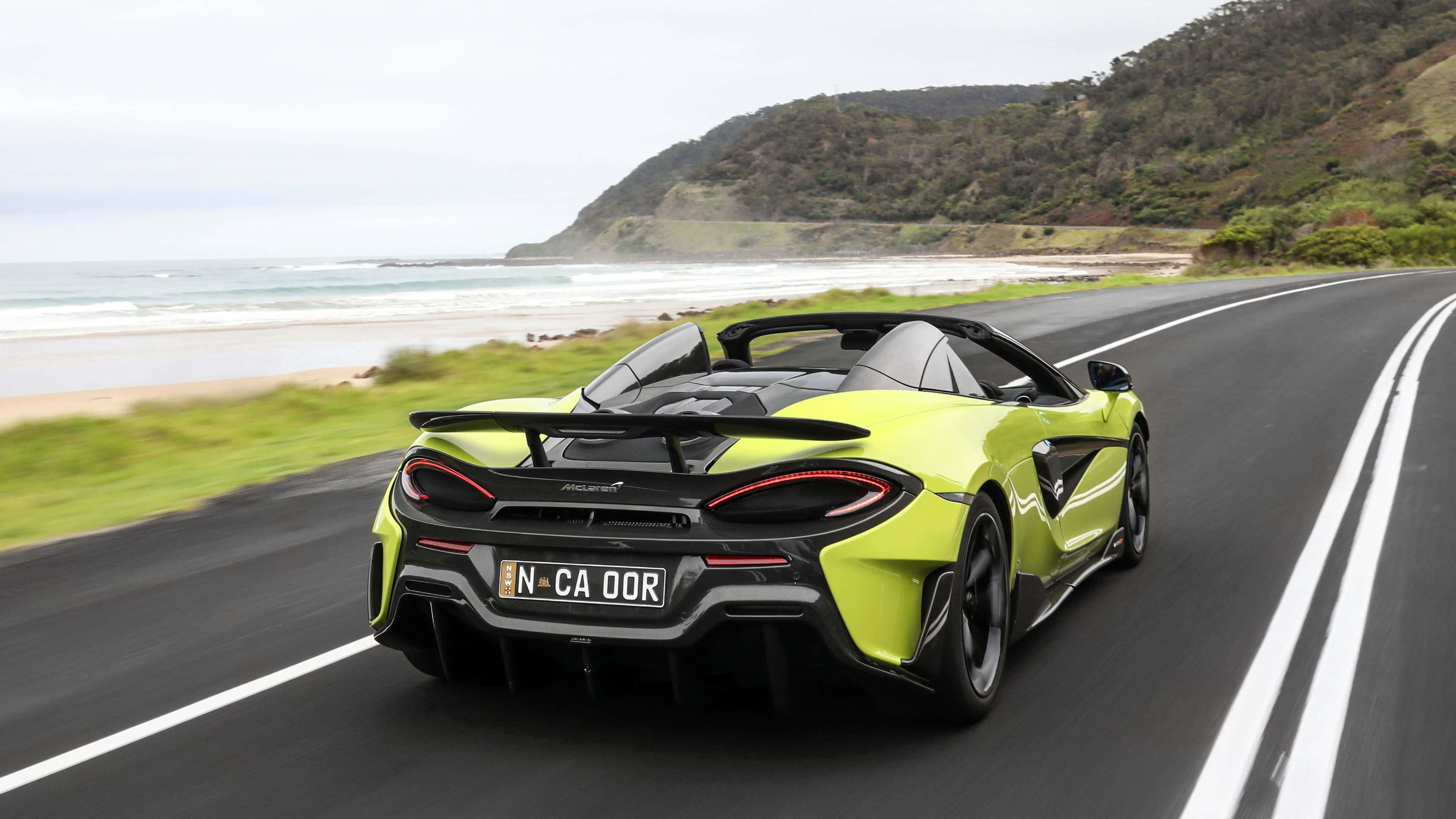 Mclaren 600lt 桌布 壁紙 — 一輛青檸綠色的McLaren跑車沿著海岸公路飛馳，背景中海浪拍打懸崖。