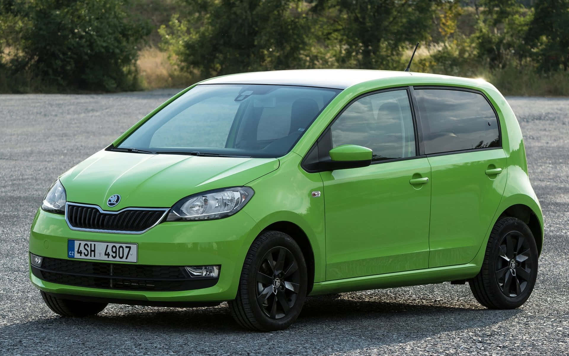 Skoda Citigo 桌布 壁紙 — 一輛充滿活力的青檸綠色斯柯達掀背車停在碎石上，背景有樹木。