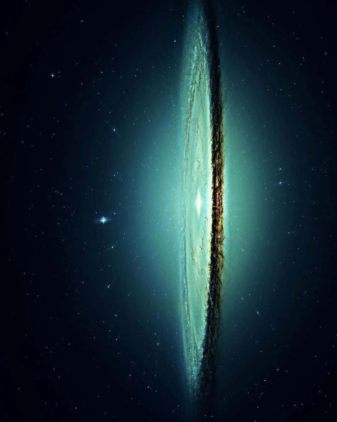  壁紙 — 令人驚嘆的側面視角，展示一個在星場中閃耀著青綠色和金色的螺旋星系。