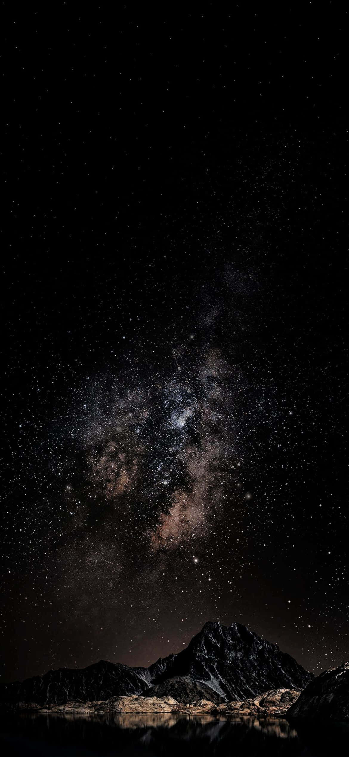銀河星系在黑暗山脈之上，倒映在夜晚的平靜水面上。