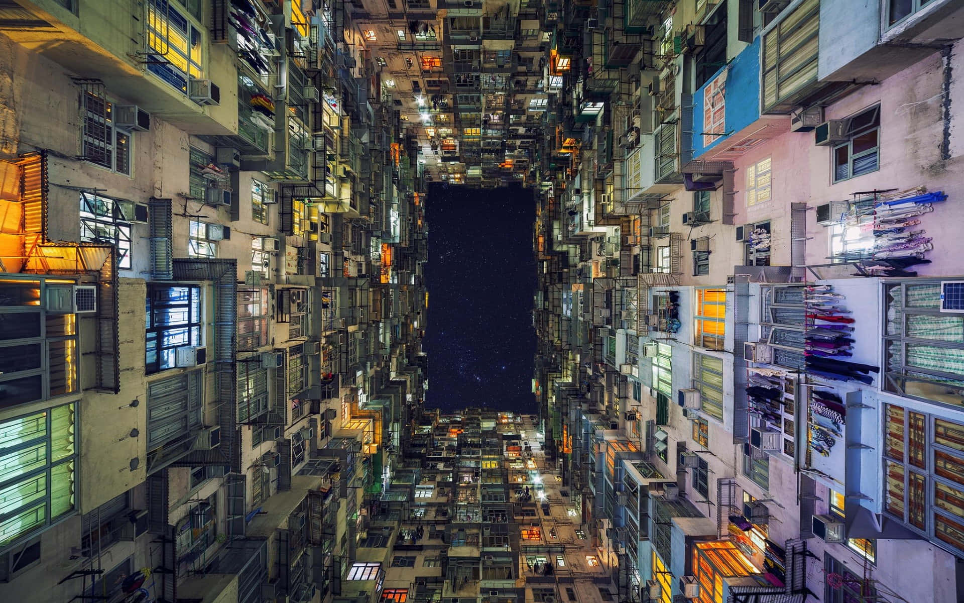夜間香港密集公寓大樓的俯瞰視角，窗戶閃爍著光芒。