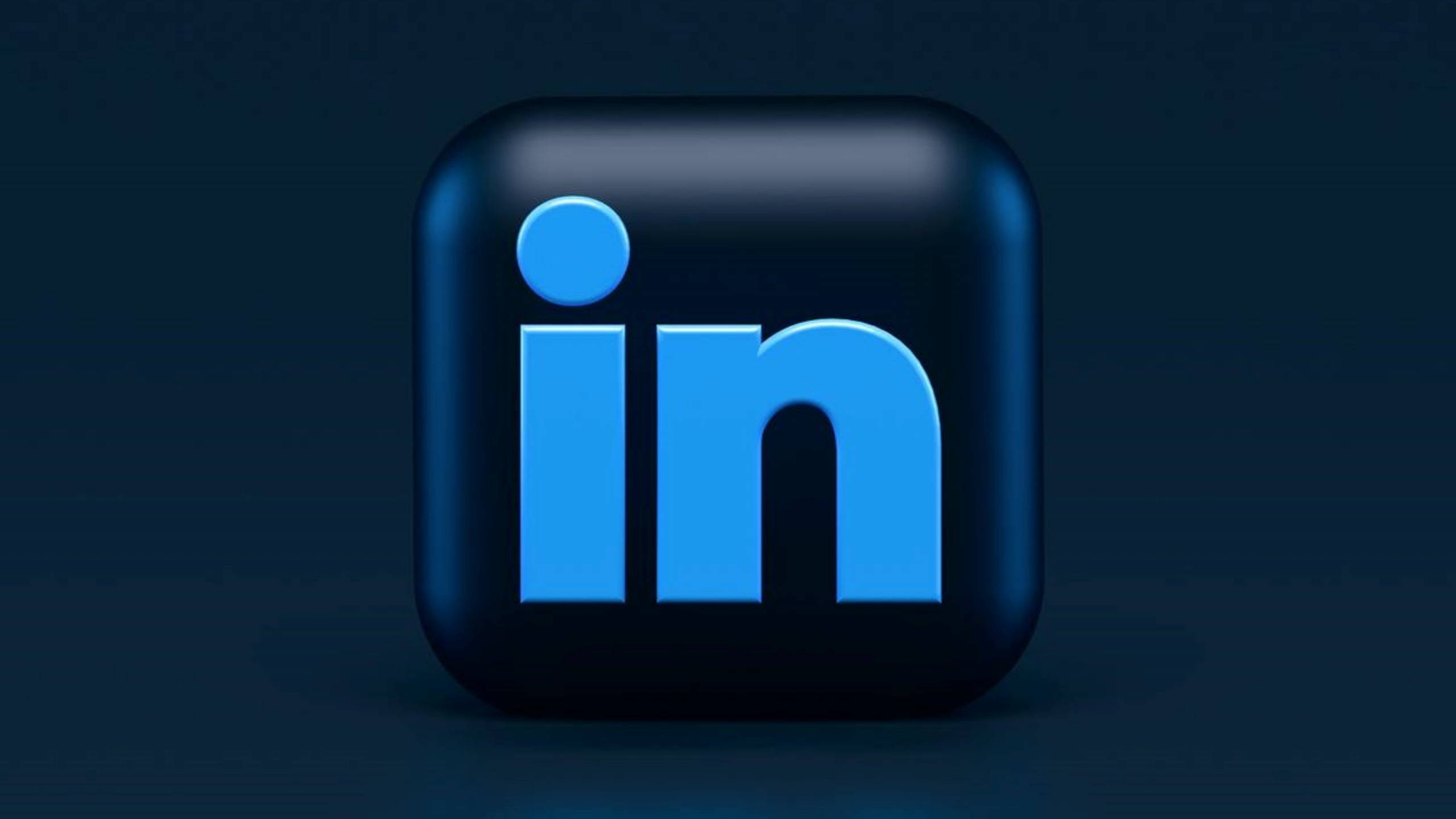 LinkedIn 藍色3D立方體 壁紙 — 一個帶有柔和照明的深色漸變背景中央，放置了一個光澤藍色LinkedIn標誌圖示。
