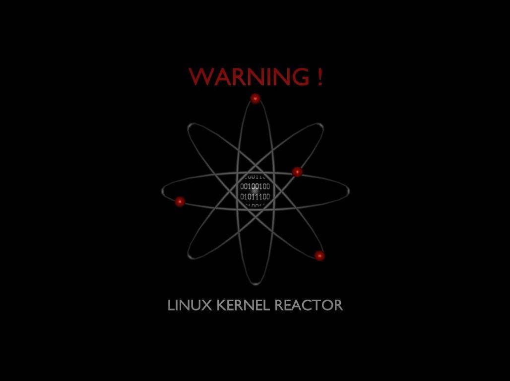 Linux核心反應器圖示 壁紙 — 純黑背景上有一個發光的紅色原子符號，核心帶有二進制代碼，上下有粗體紅色警告文字。