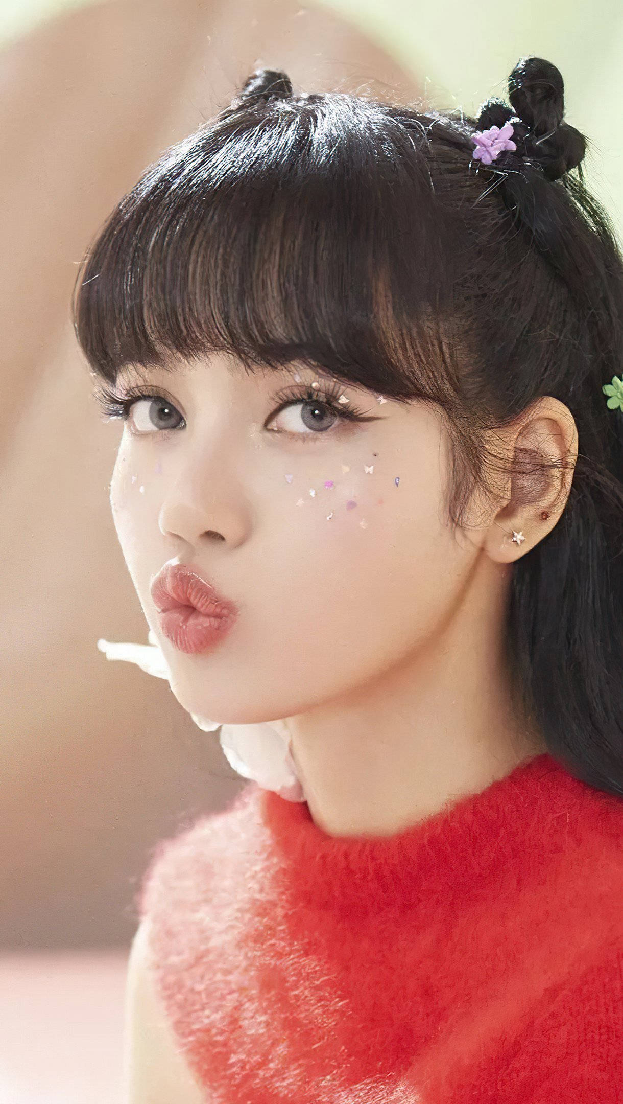 Lisa BLACKPINK《Ice Cream》MV高清壁紙 壁紙 — 一位年輕女性，深色頭髮梳成髮髻，臉頰上有亮片，穿著蓬鬆的紅色毛衣，正在飛吻。