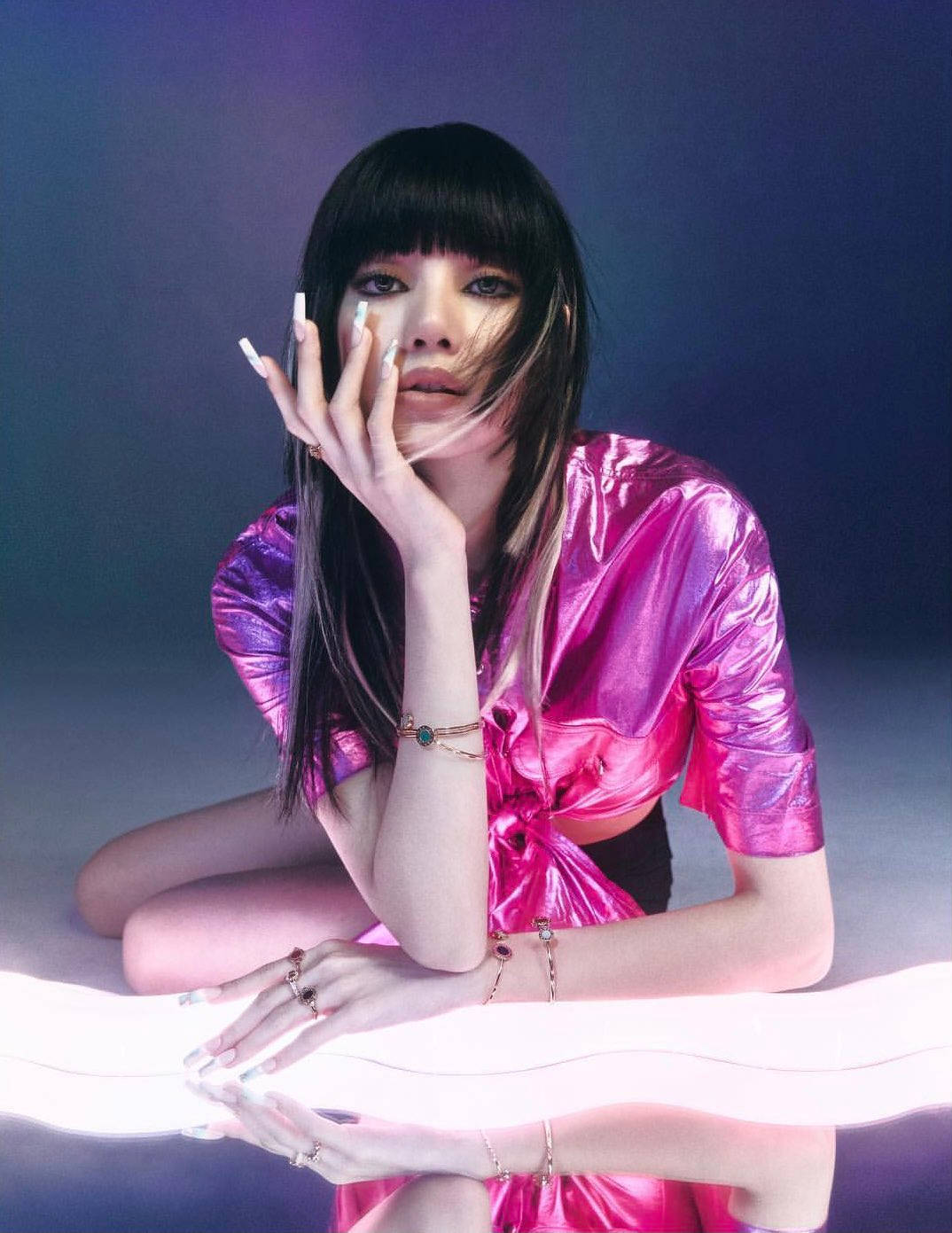 Lisa BLACKPINK《W Korea》雜誌高清寫真 壁紙 — 一位身穿閃亮粉紅色服裝的女性，在漸變紫藍色背景前，將手靠近臉部擺姿勢。