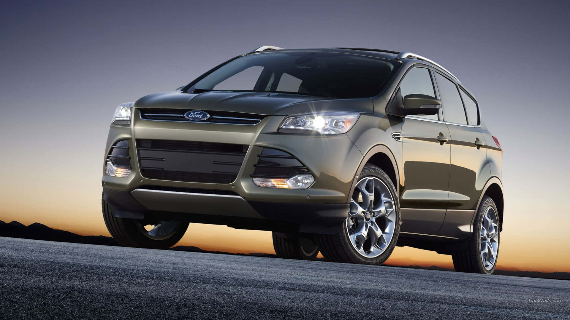 Ford Escape 桌布 壁紙 — 一架流線型橄欖綠色福特Escape SUV在夕陽下閃耀，行駛在沙漠公路上，遠方有山脈。