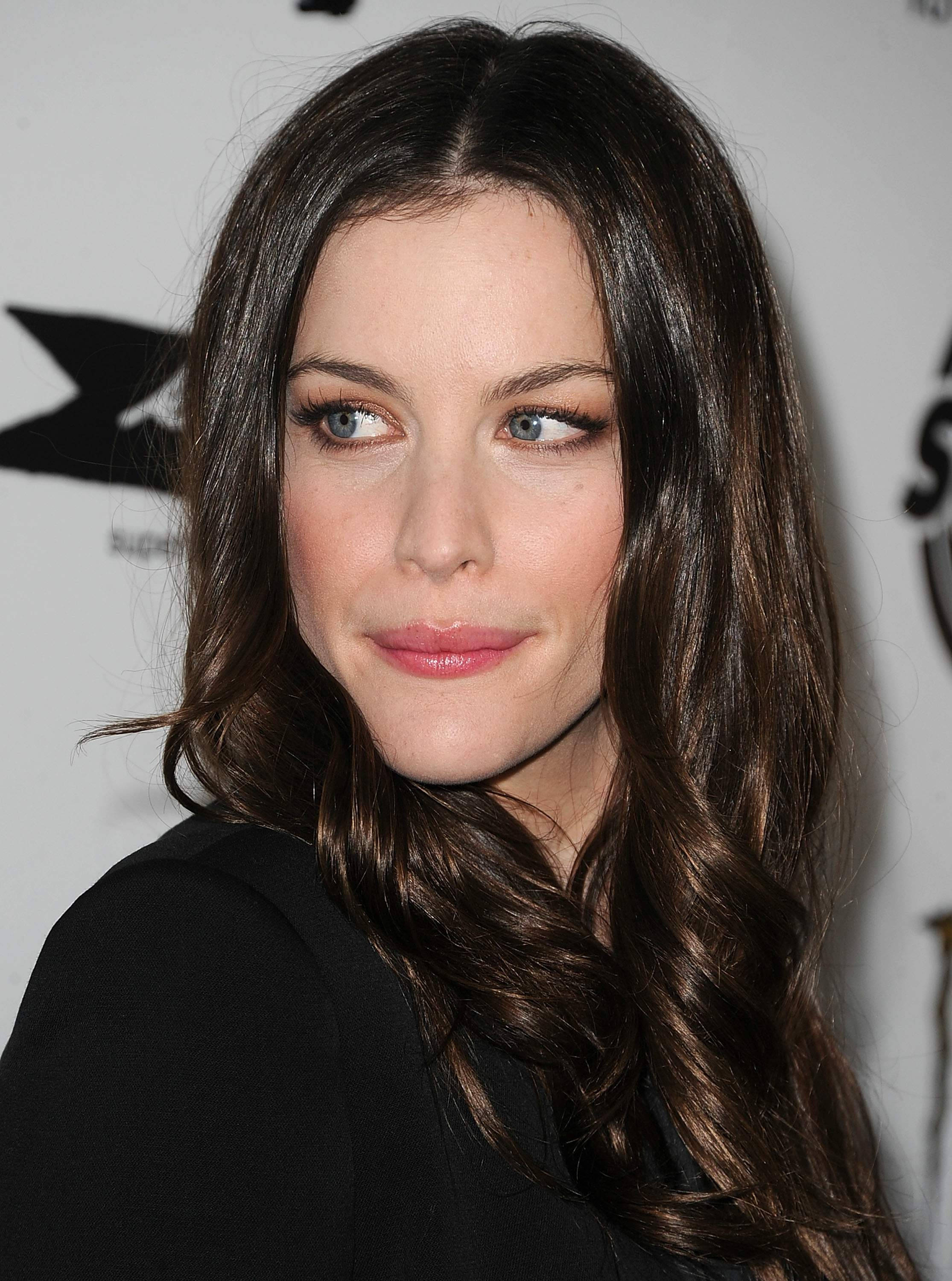 Liv Tyler 名人模特兒 壁紙 — 一位長著棕色長波浪髮和藍眼睛的女性側面特寫肖像。