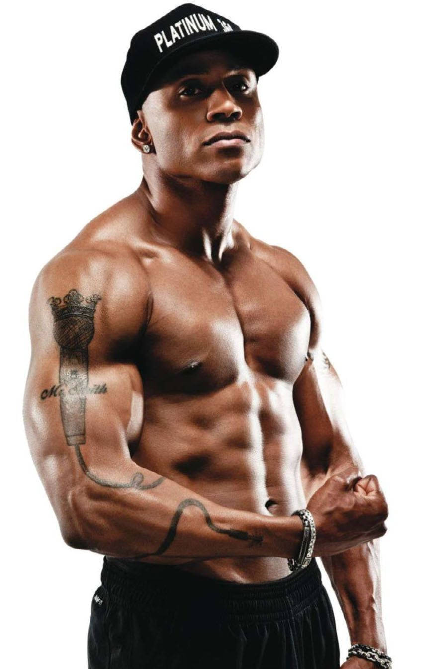 LL Cool J 在1990年專輯拍攝中展示肌肉 壁紙 — 一個肌肉發達、有紋身、戴黑色鴨舌帽的男人，在純白背景前自信地擺姿勢。