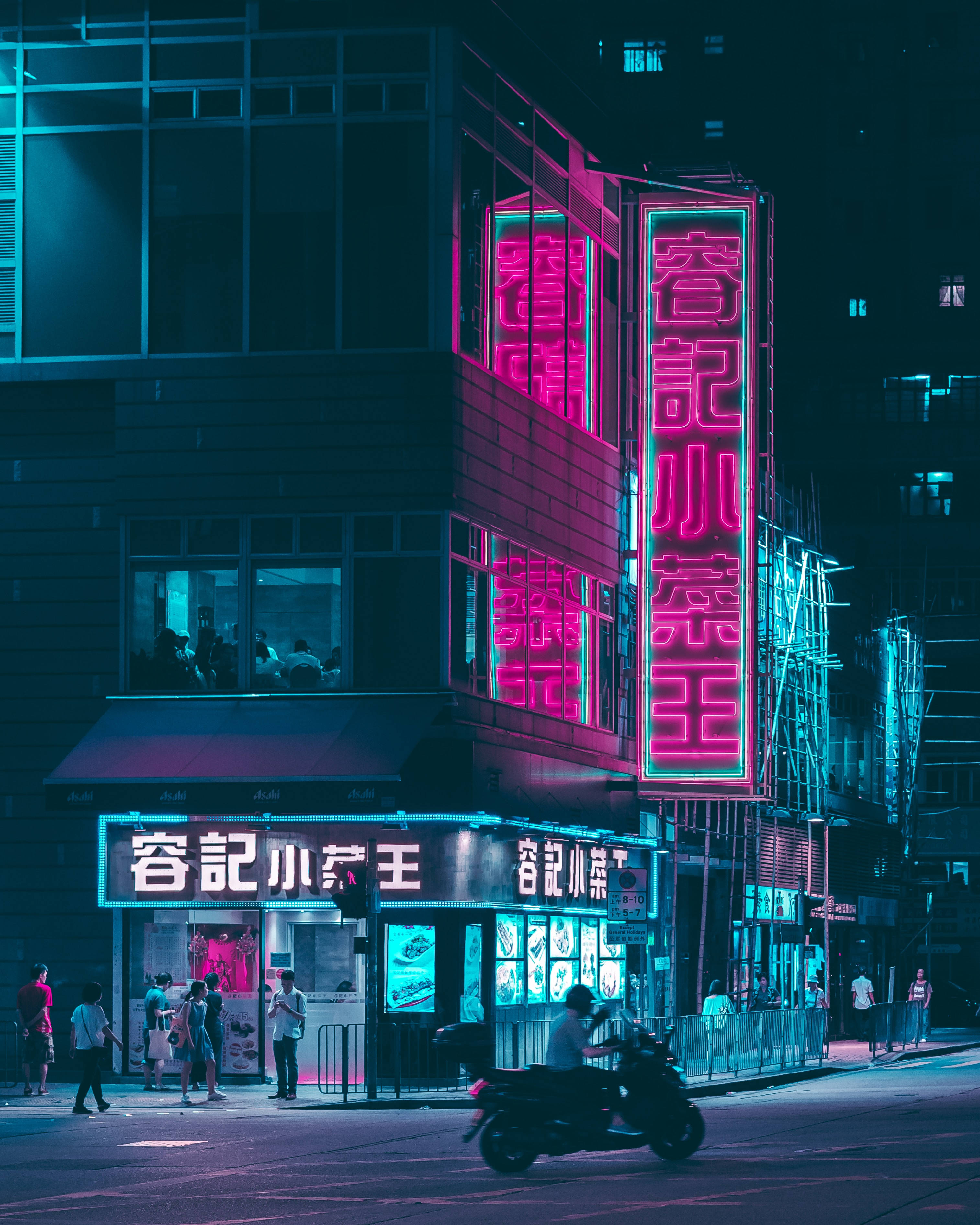 Lo Fi iPhone 夜景 壁紙 — 充滿活力的霓虹燈在黑暗的城市夜晚中發出粉紅色和青色的光芒，行人與電單車在繁忙的街道上穿梭。