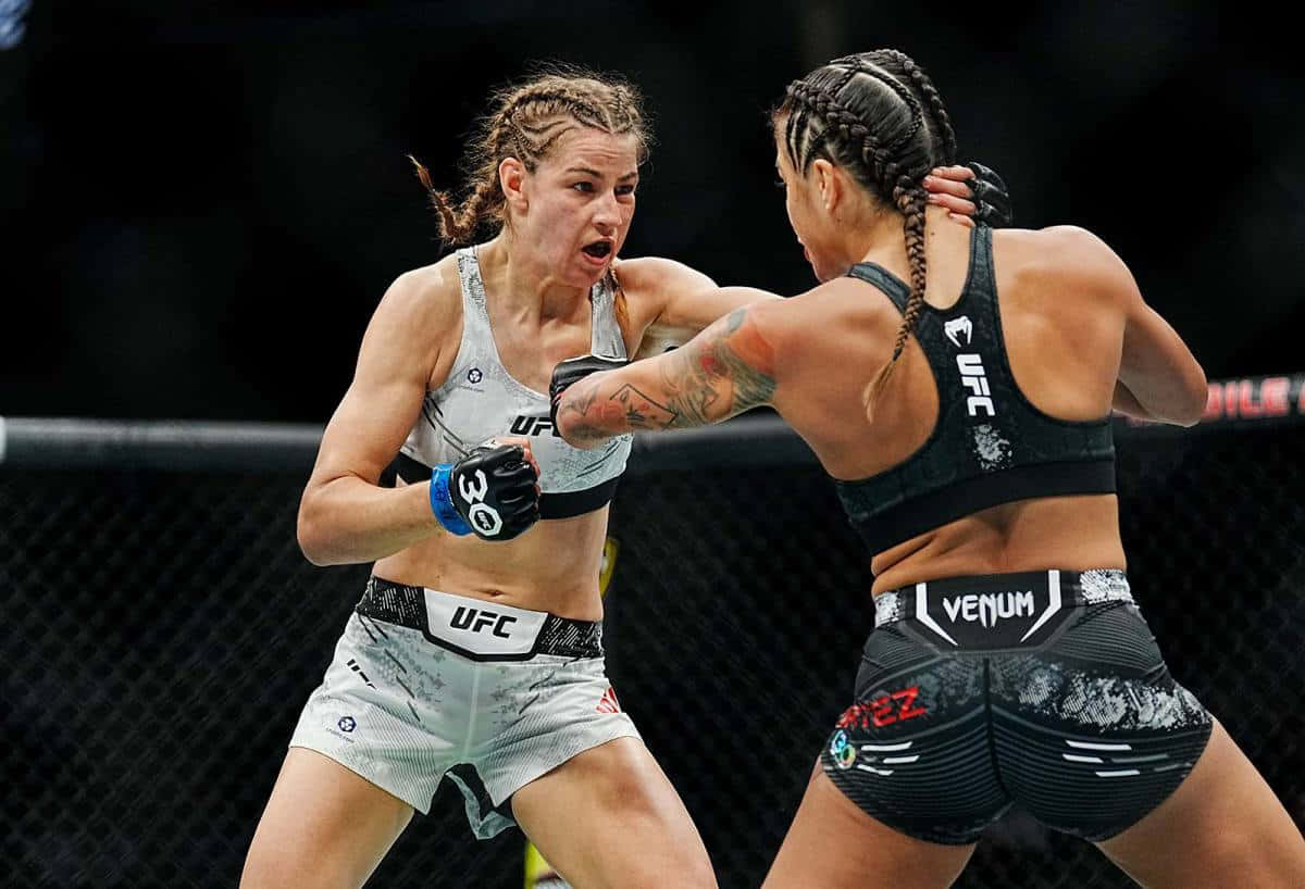  壁紙 — 兩名女性MMA拳手在激烈的鐵籠賽中交鋒，其中一人打出強力一拳。