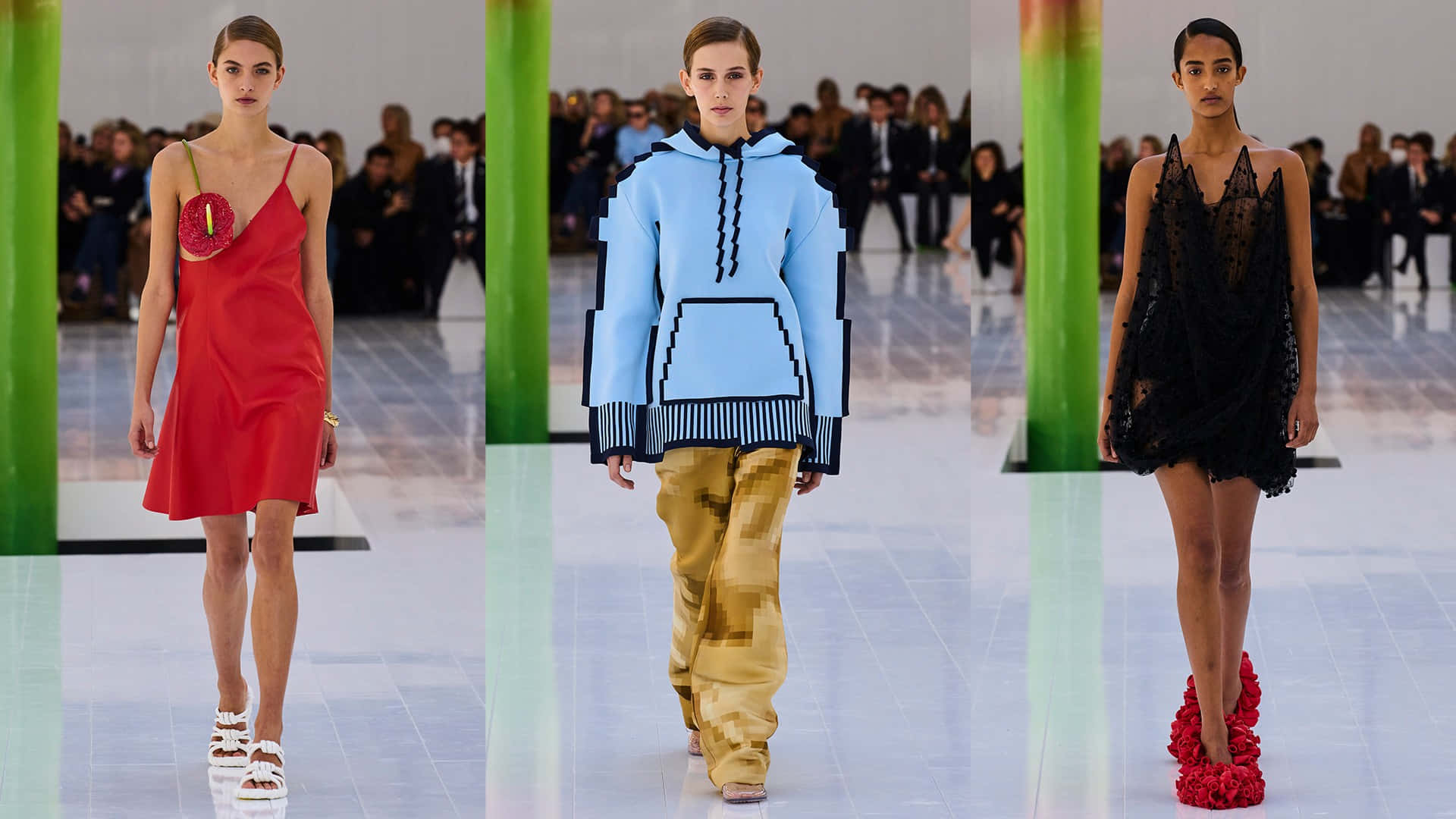 現代優雅 - Loewe 2023春夏系列 壁紙 — 三位模特兒在閃亮的T台上走秀，穿著前衛服裝，包括紅色連衣裙、像素風連帽衫和帶花卉高跟鞋的黑色蕾絲連衣裙。
