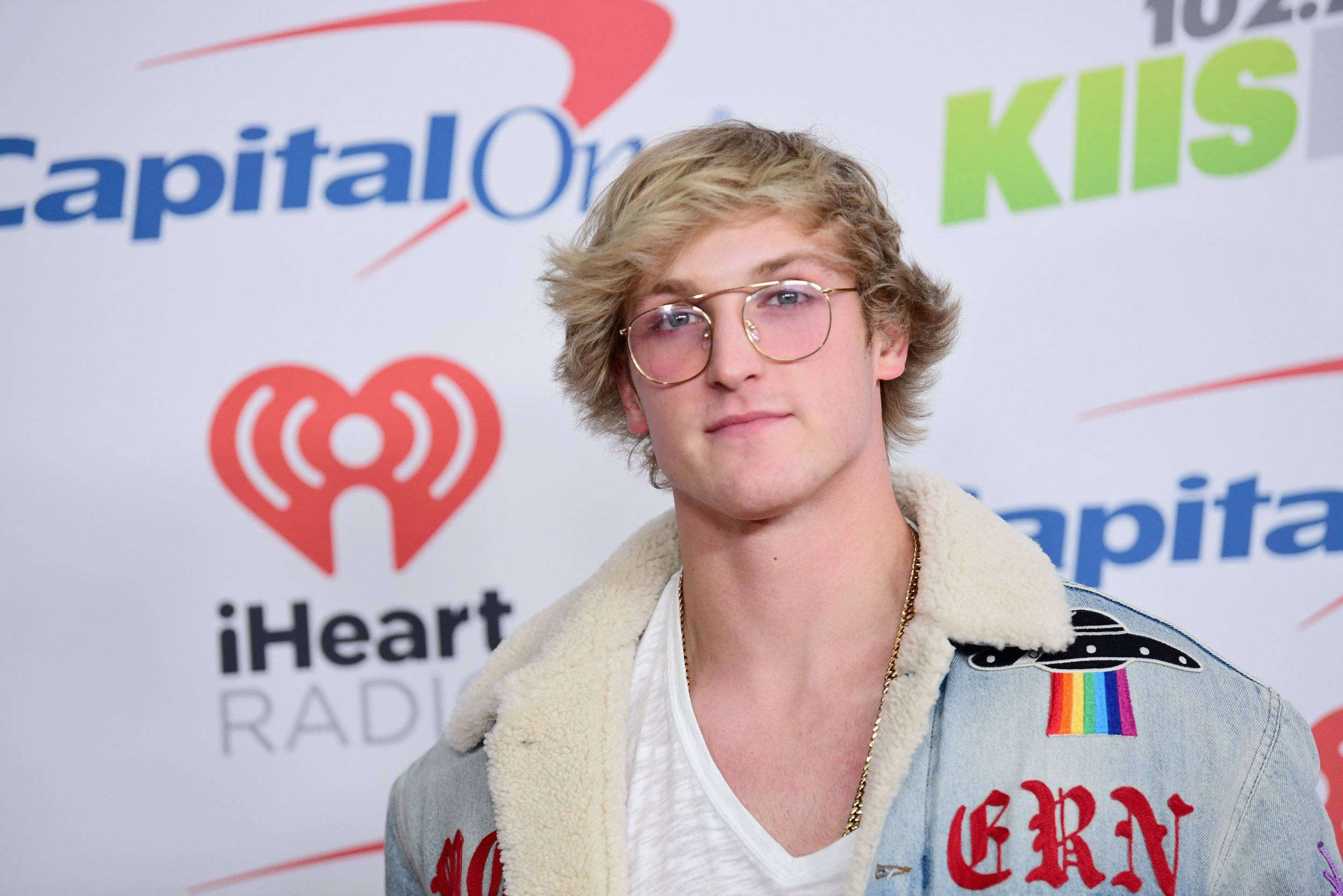 Logan Paul 身穿 Gucci 丹寧夾克 壁紙 — 一位金髮戴眼鏡的年輕男子，在Capital One iHeartRadio活動中穿著帶有彩虹補丁的牛仔外套。