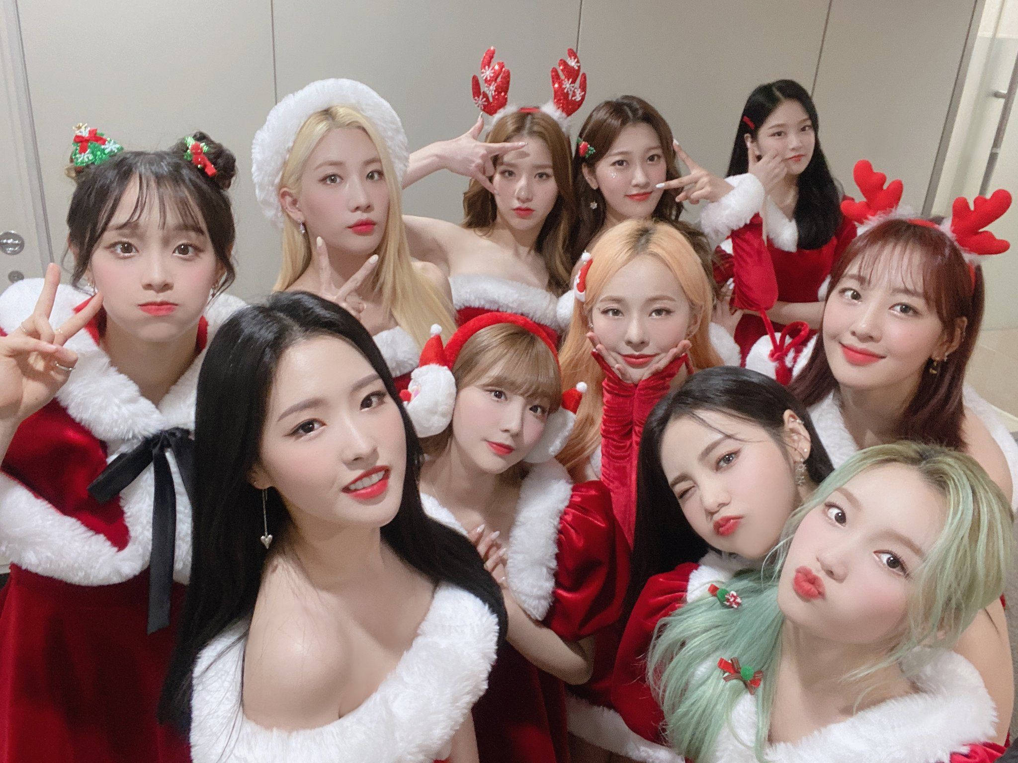 LOONA聖誕風格聖誕老人服裝 壁紙 — 九位年輕女性身穿節日紅白聖誕老人服裝，在室內戴著馴鹿角，表情俏皮，愉快地擺姿勢。