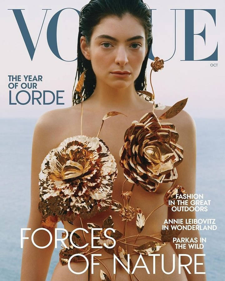 Lorde 為《Vogue》十月號封面拍攝 壁紙 — 一位濕髮女性佩戴金色金屬花卉裝飾，背景是模糊的海洋，登上Vogue雜誌封面。