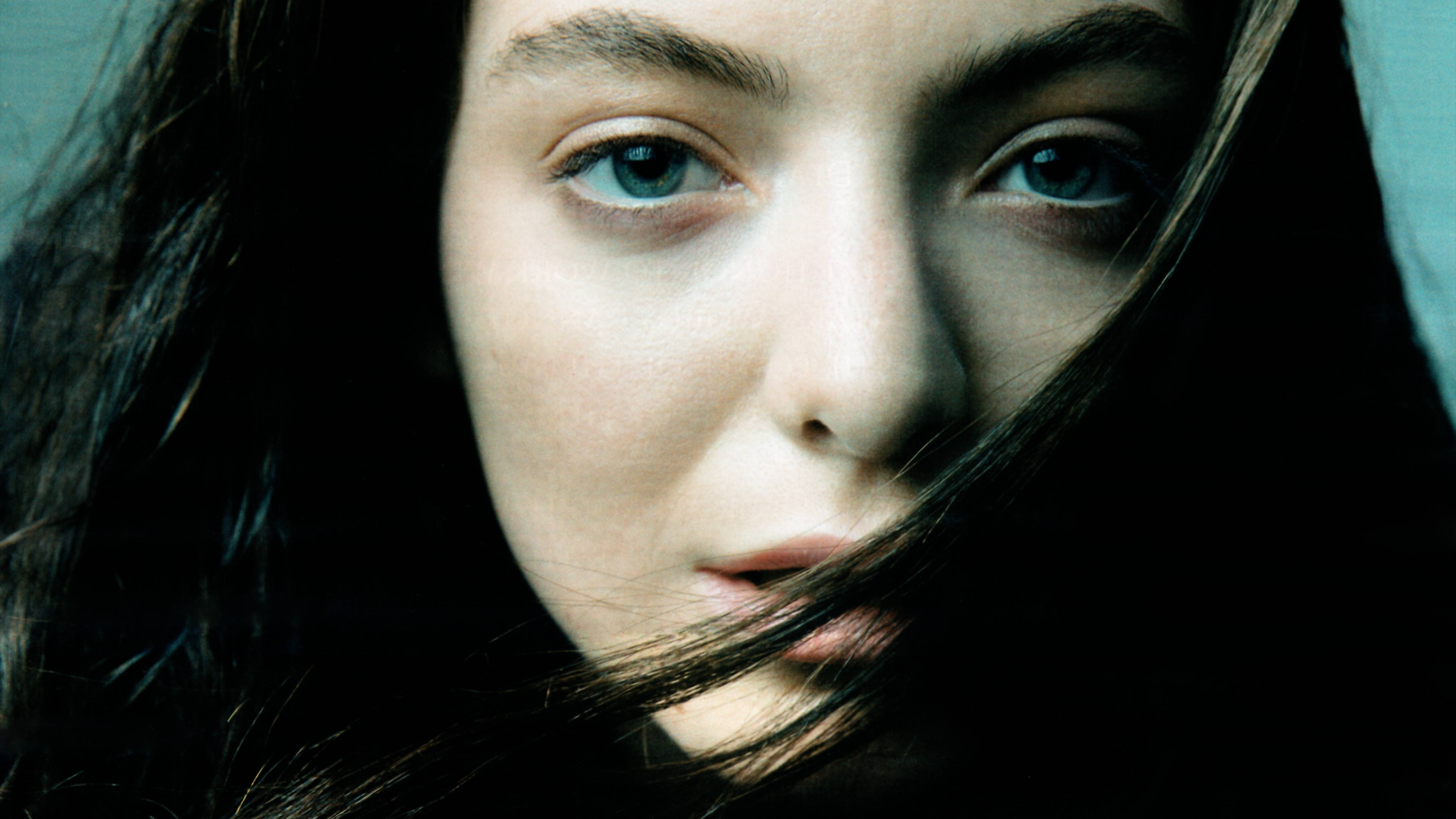 Lorde《Billboard》雜誌拍攝 壁紙 — 柔光下，一名女子近距離肖像，擁有引人注目的藍色眼睛和部分遮蓋臉龐的深色頭髮。
