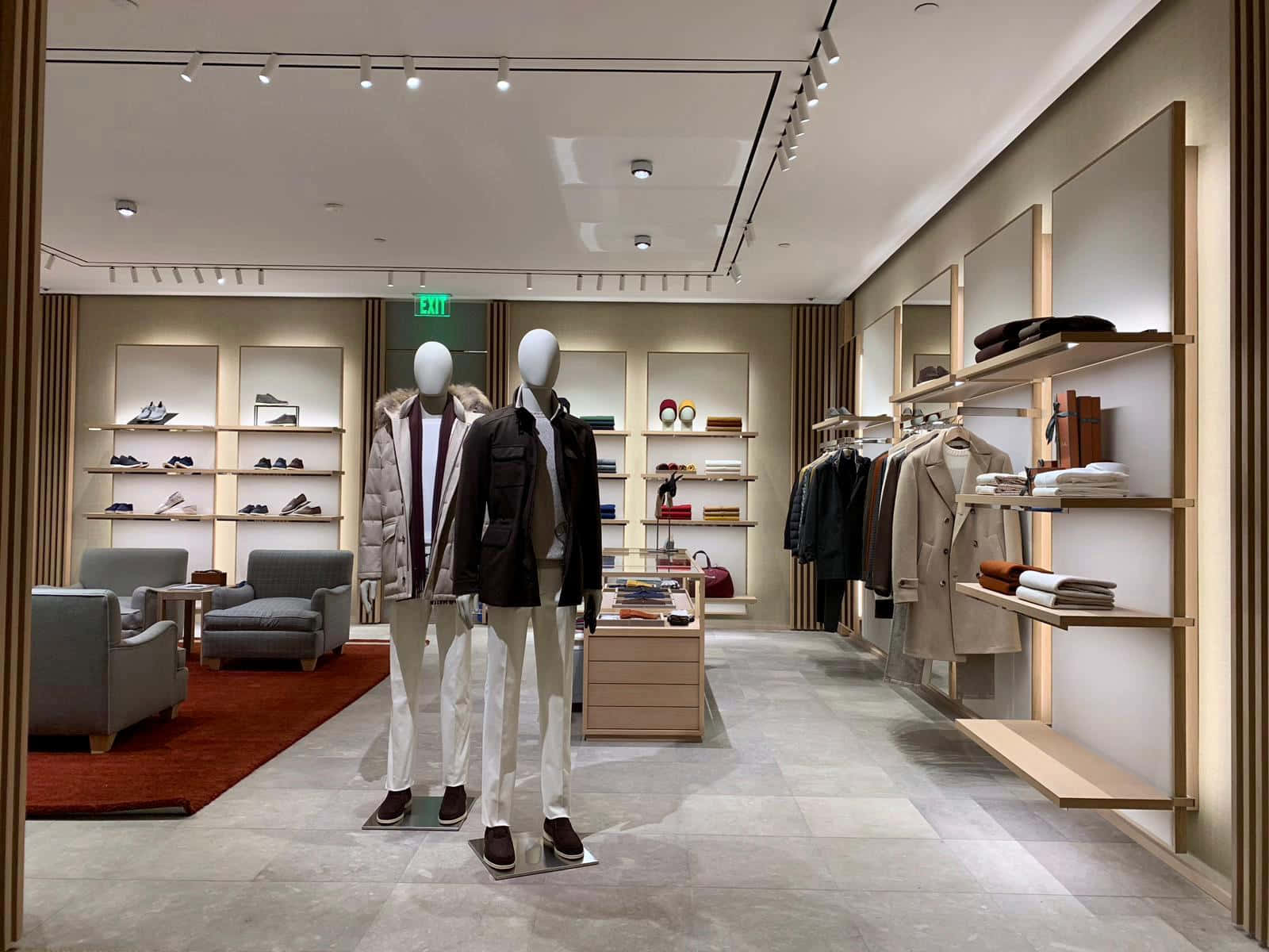 體驗義大利奢華 —— Loro Piana 金斯伍德旗艦店 壁紙 — 現代男士服裝店，人體模型穿著時尚外套，整齊排列的鞋子和配件貨架，在明亮的軌道燈光下。