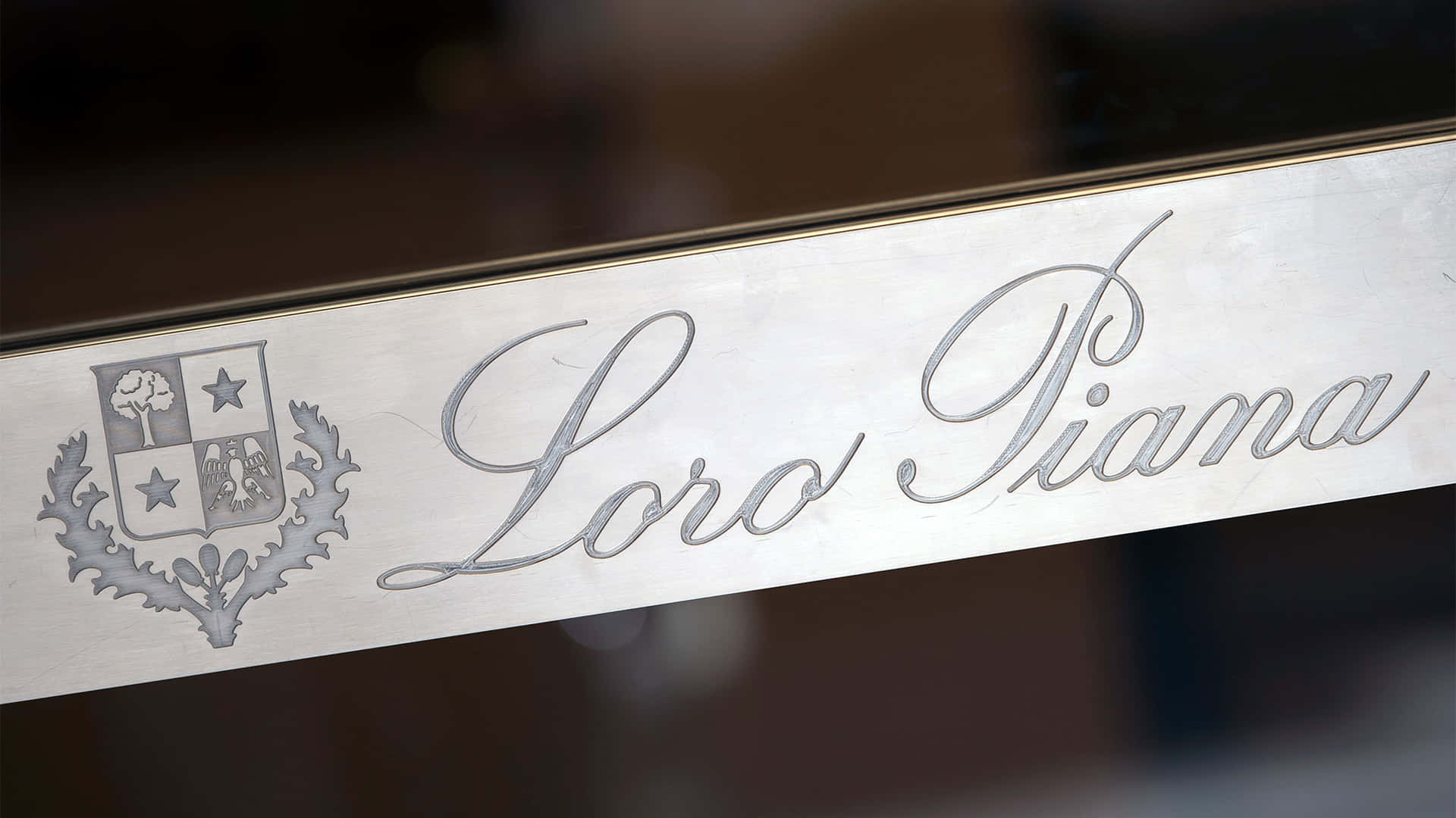 銀色刻有Loro Piana標誌和徽章，位於拋光表面上。