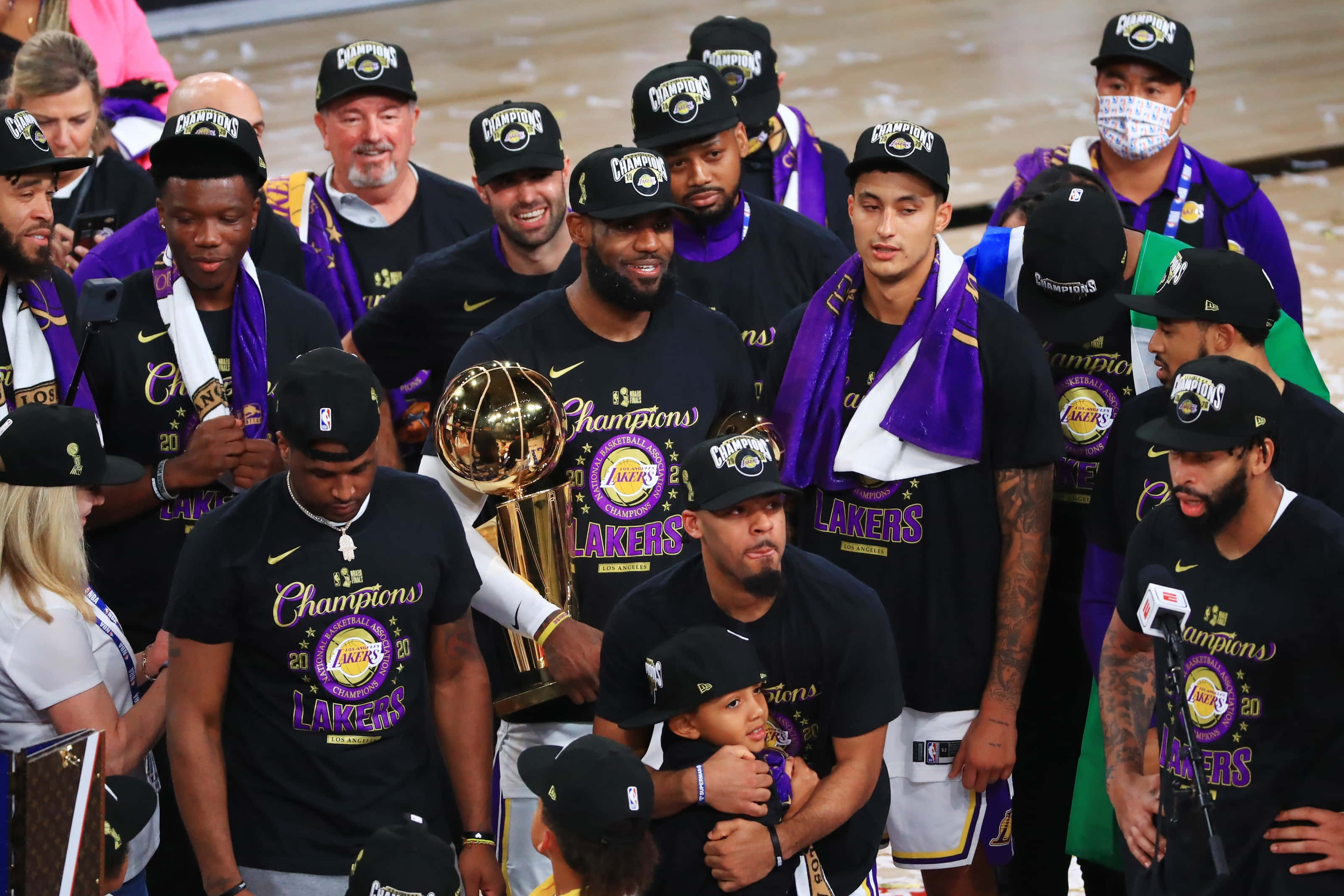 Lakers 2020 桌布 壁紙 — 洛杉磯湖人籃球隊穿著黑色和紫色冠軍裝備，手持獎盃慶祝冠軍勝利。